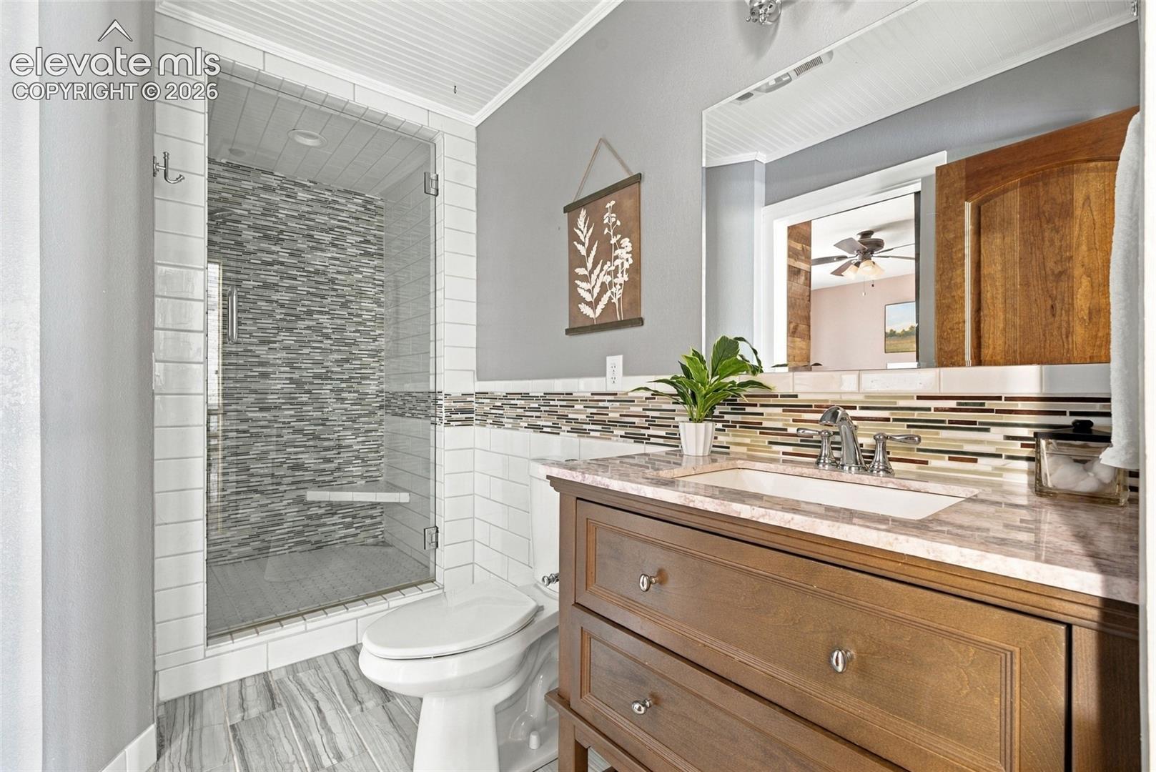 ensuite bathroom Glass-enclosed shower with a mosaic tile wall and built-in bench