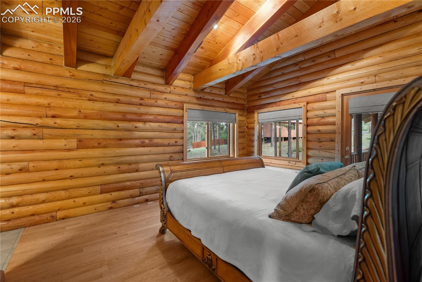 Bedroom with wood finished floors, wood ceiling, and log walls