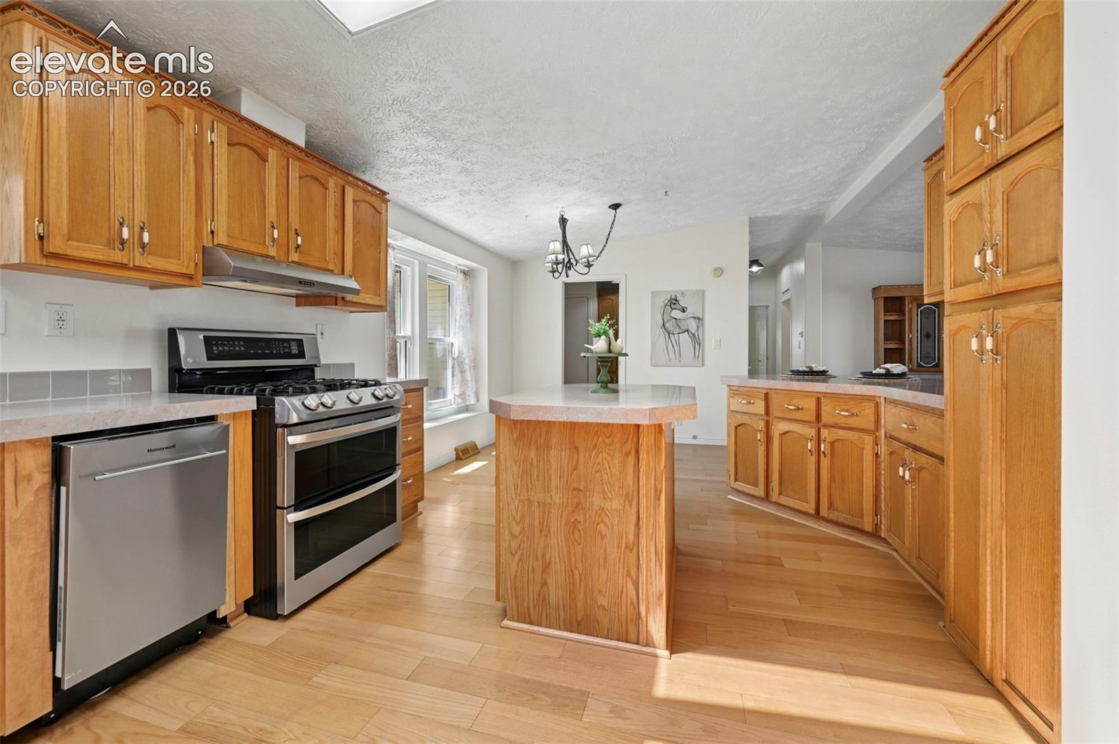 Kitchen featuring wood-finish cabinetry, stainless steel appliances, a center island with countertop, and wood-finish flooring