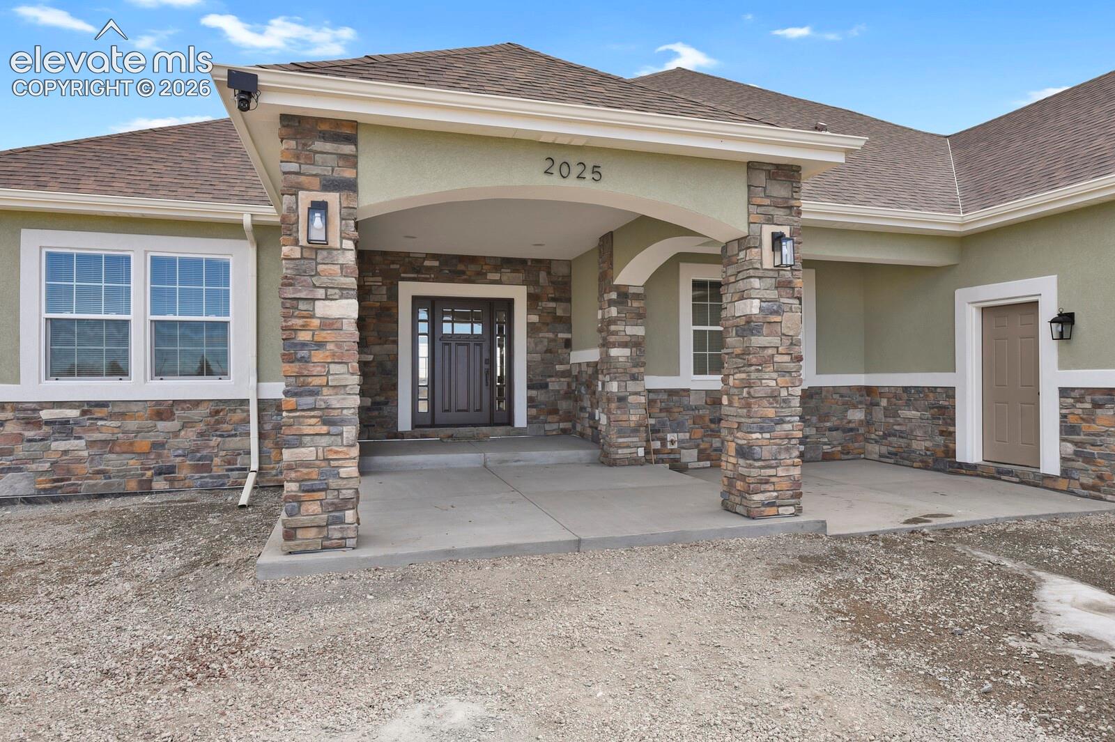 Stone façade entry with a covered porch, arched details, and decorative outdoor lighting