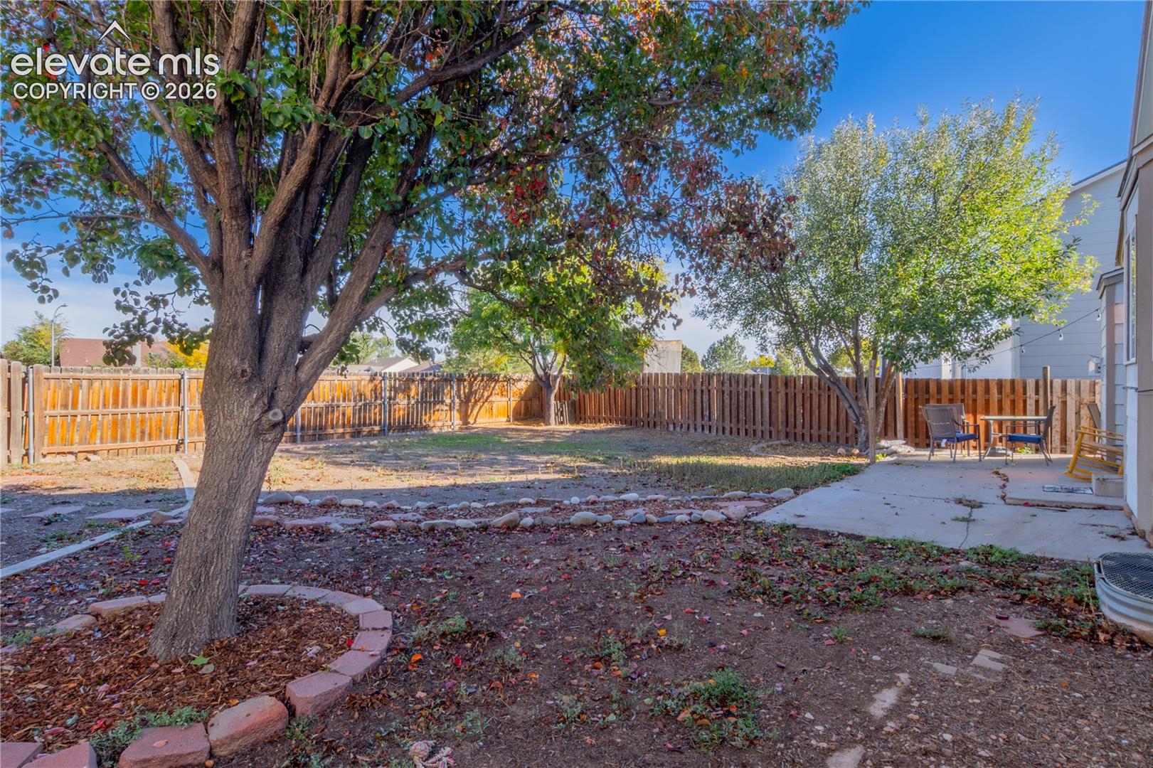 Concrete patio and stone-bordered landscaping create an inviting setting for outdoor seating.