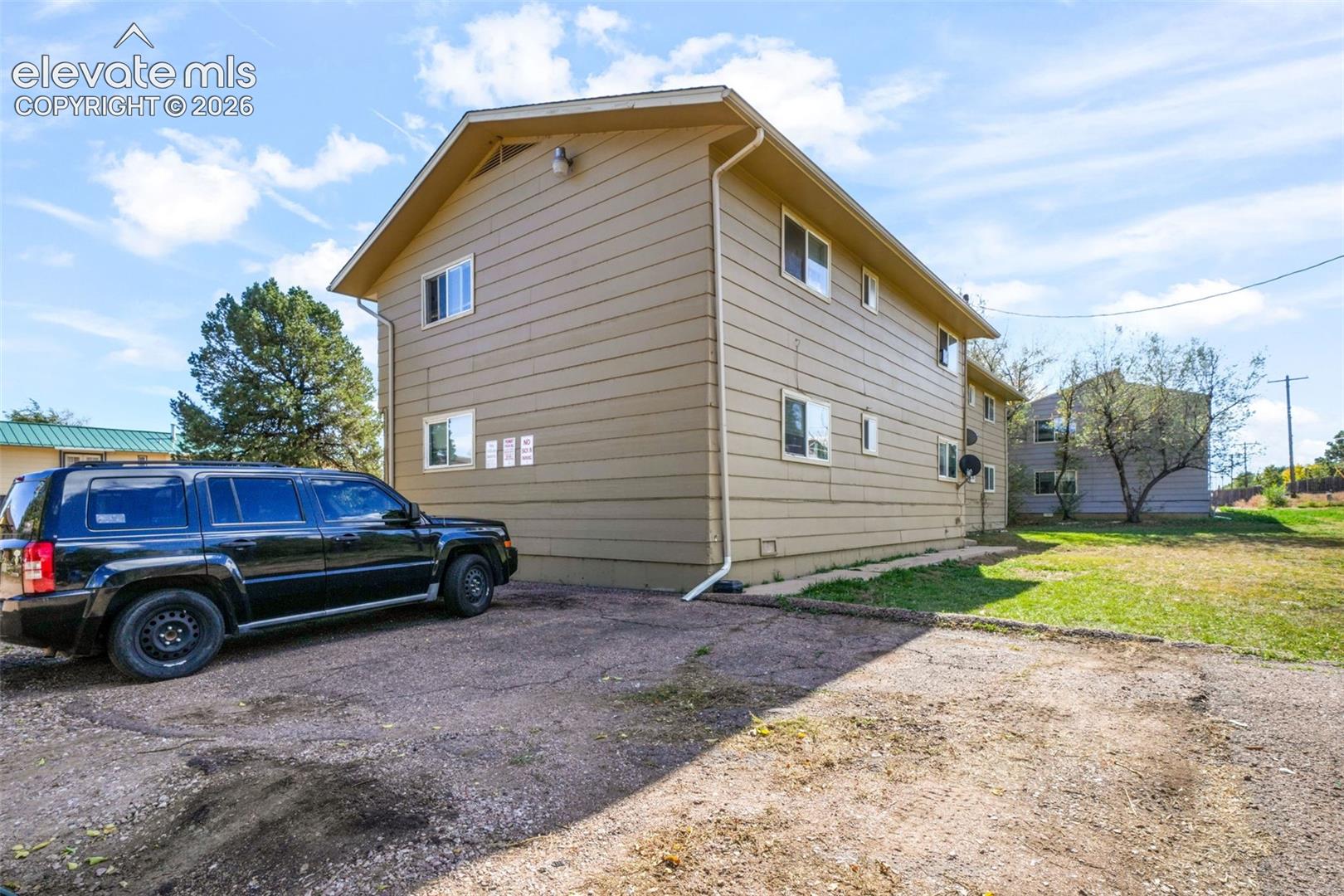 Two-story exterior featuring horizontal lap siding, a gabled roofline, and an asphalt-surfaced parking area