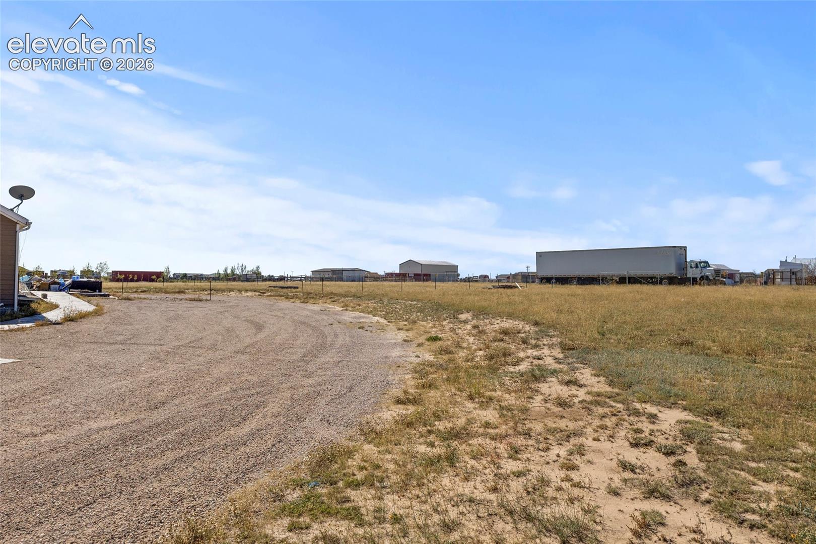 Expansive parcel of land featuring a gravel driveway and perimeter wire fencing