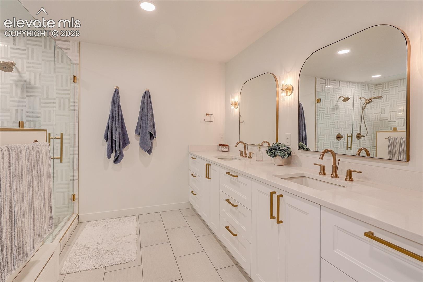 Double vanity featuring undermount sinks and brass-finish fixtures