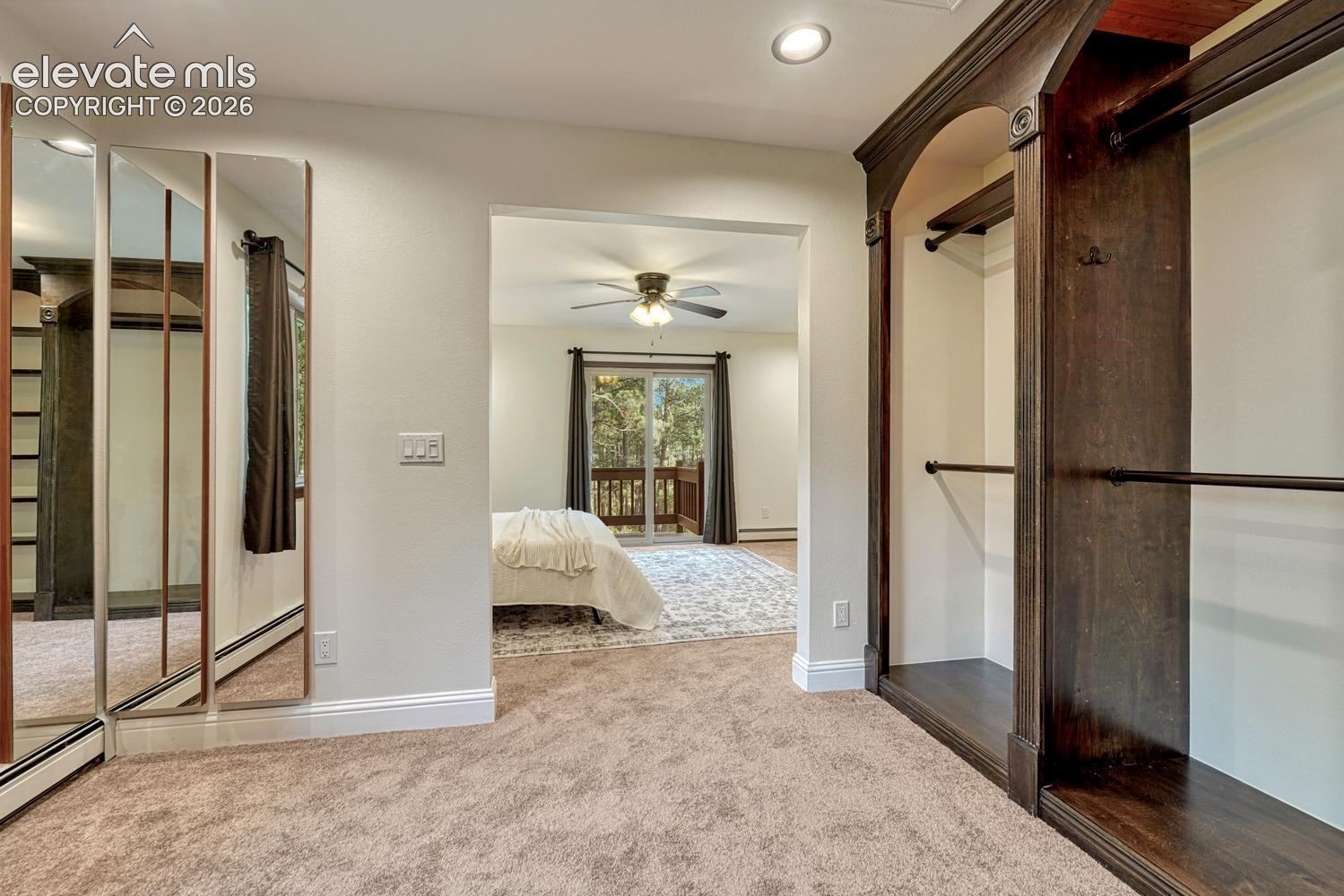Built-in dark wood shelving and cabinetry, floor-to-ceiling mirrored closet doors, recessed lighting, and wall-to-wall carpeting