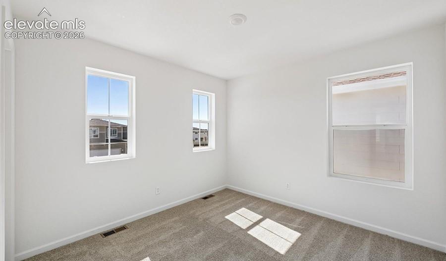Neutral-toned wall-to-wall carpeting, crisp white walls, and triple multi-pane windows providing natural light