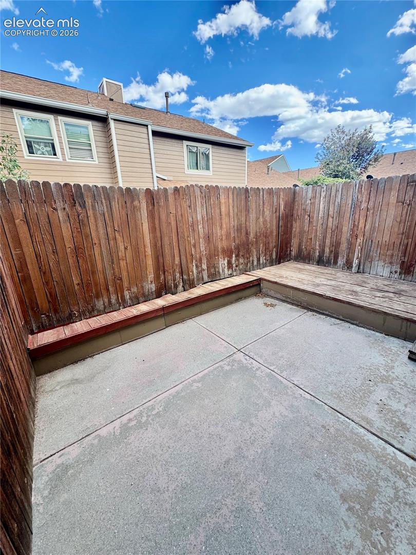 Private outdoor space featuring concrete paving and a raised wooden deck
