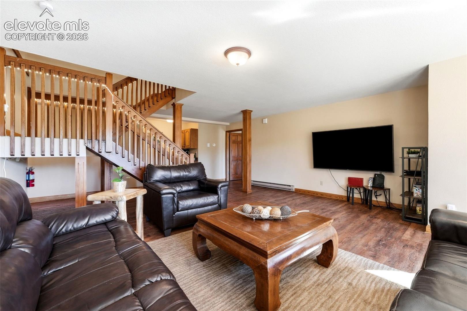 Wood-finish flooring throughout, with a prominent wood staircase featuring open balusters, and a built-in entertainment wall