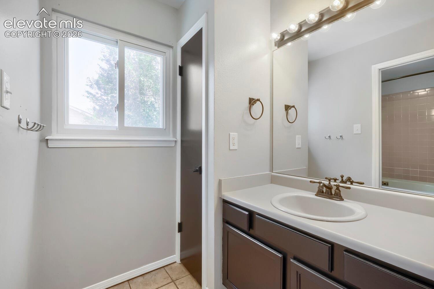 Bathroom vanity featuring an integrated sink, broad mirror, and overhead lighting fixture