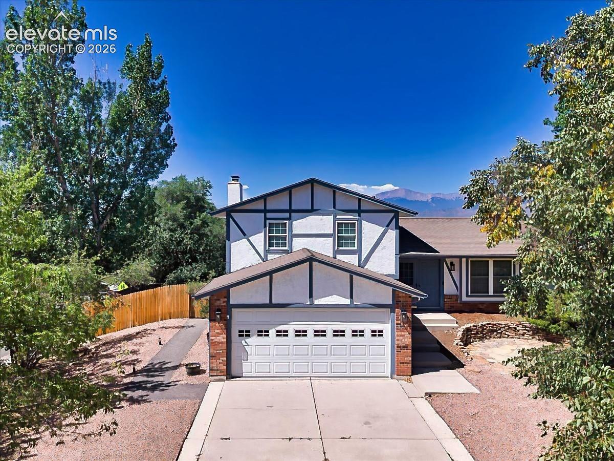 Charming Tudor-inspired exterior with mature landscaping, an attached two-car garage, and attractive curb appeal on a spacious corner lot.