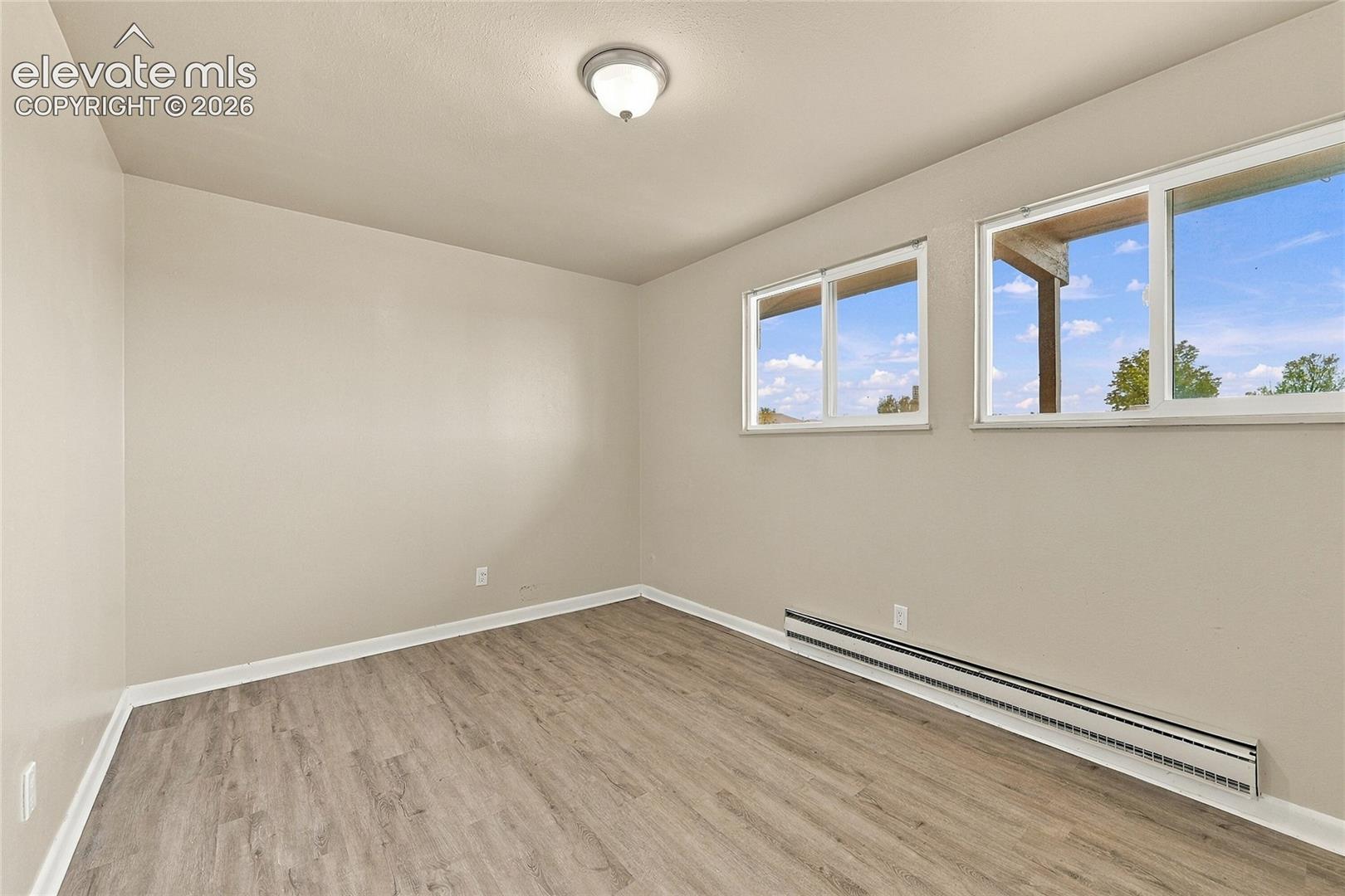 Neutral-toned room featuring wood-finish flooring, dual sliding windows, and a ceiling-mounted light fixture