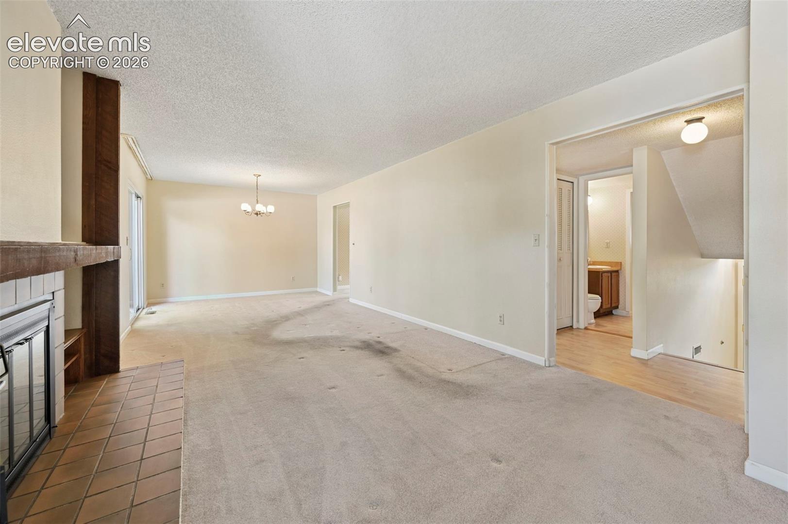 Fireplace with tile hearth and wood mantel opens to dining area