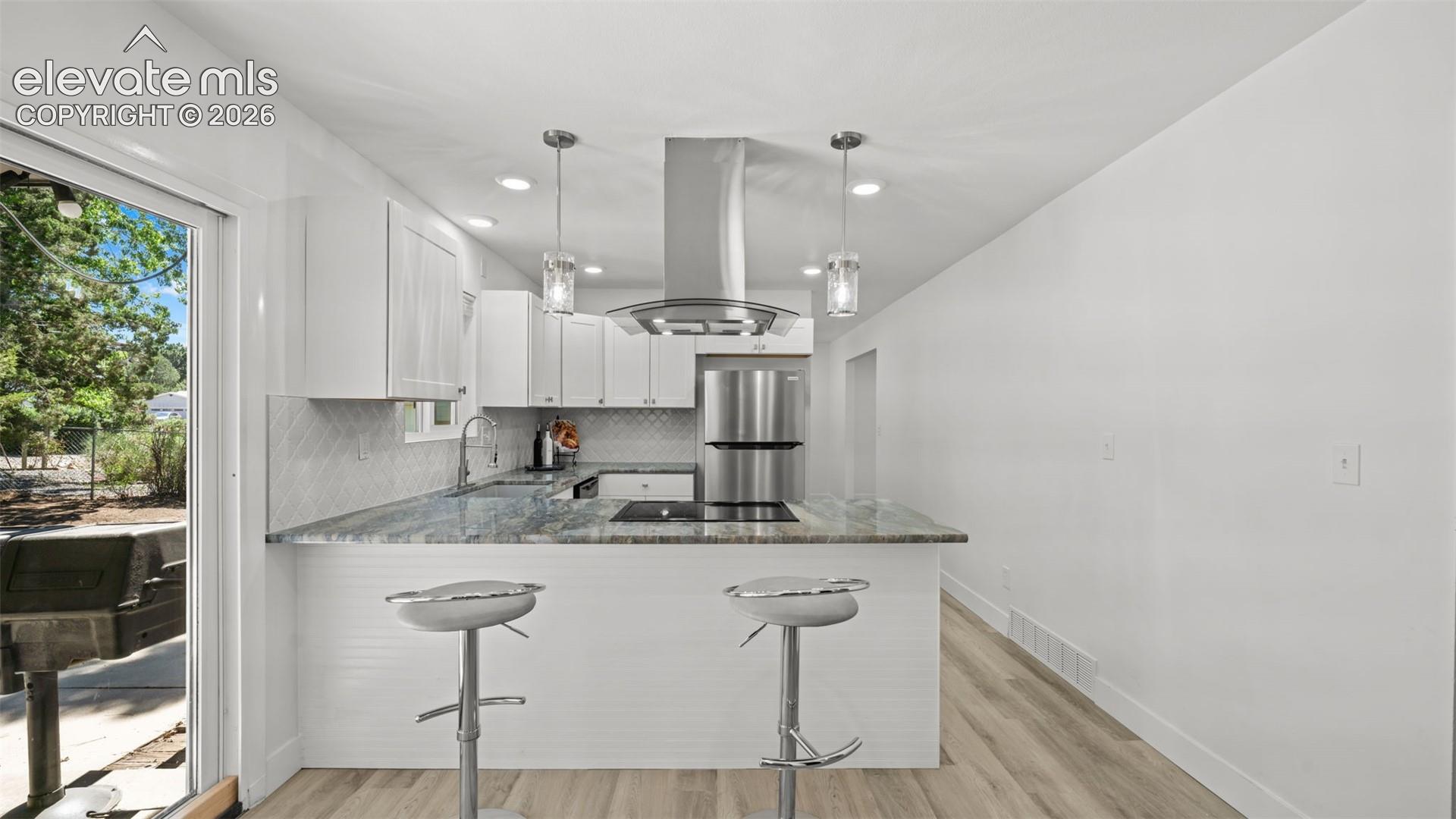 Kitchen featuring white cabinetry, stainless steel appliances, recessed lighting, and wood-finish flooring