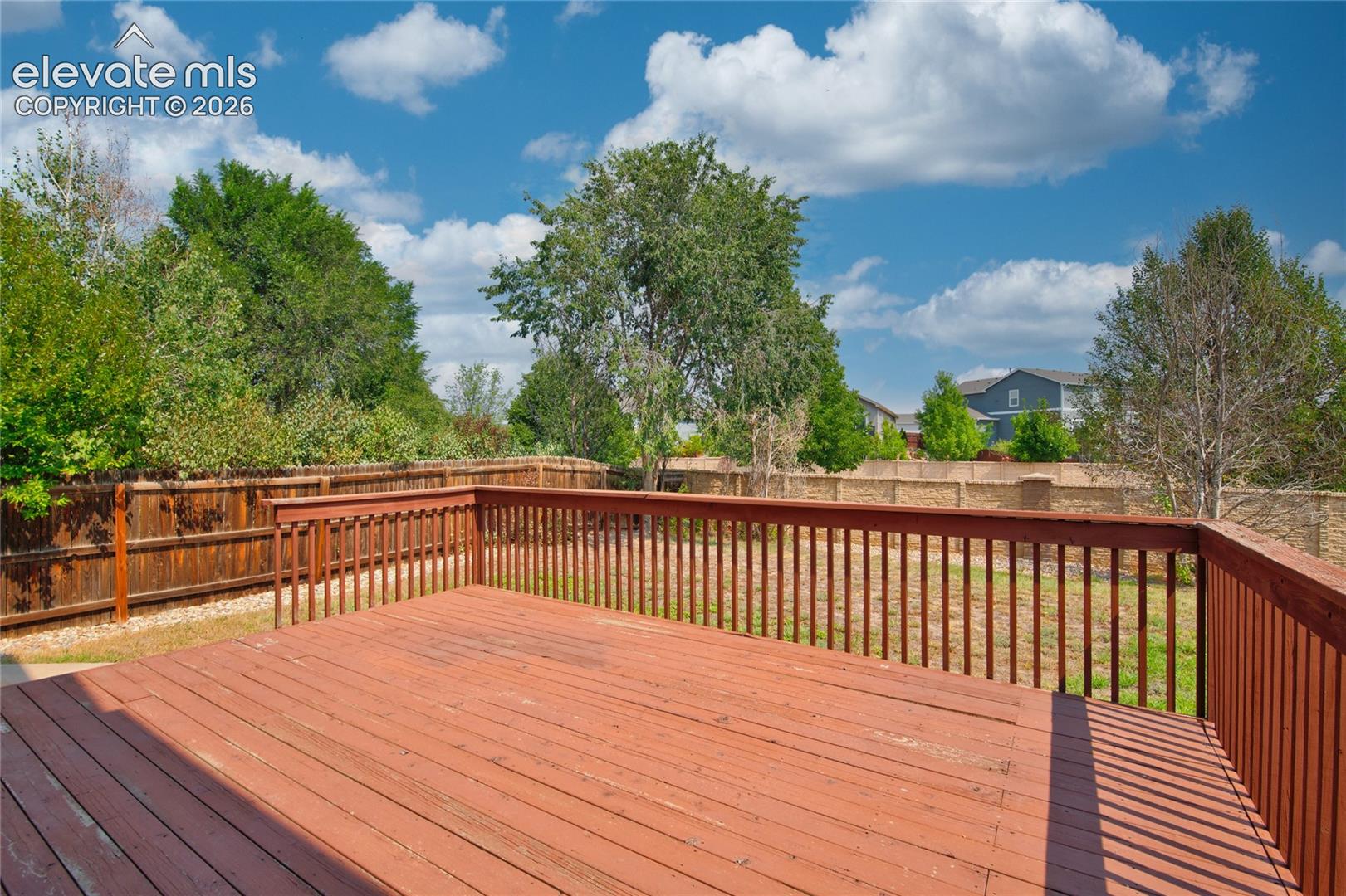 Spacious outdoor deck with wood railing, offering an open-air area for entertaining