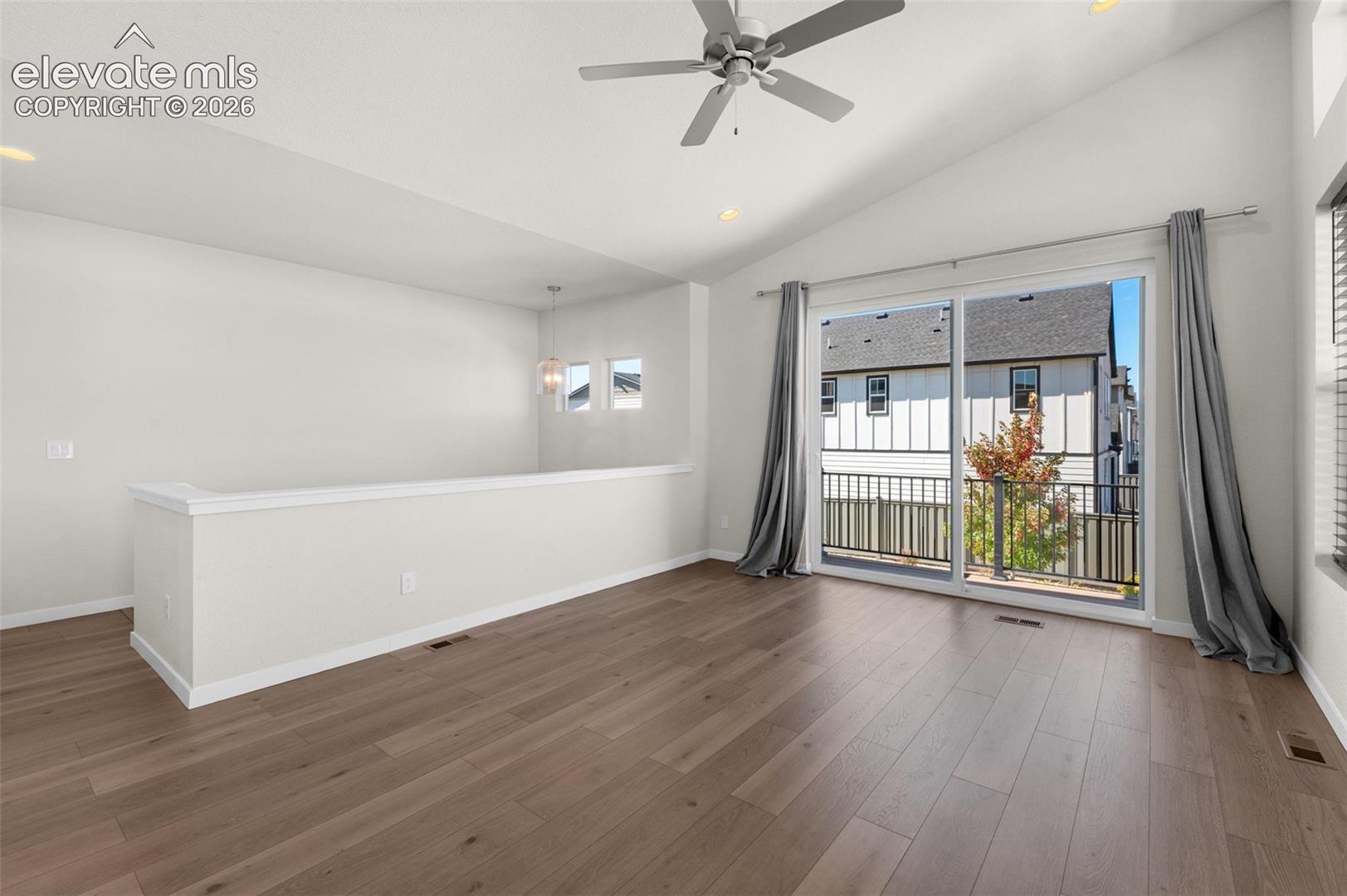 Vaulted ceilings with a ceiling fan, wood-finish flooring, half-wall partition, recessed lighting, and sliding glass door leading to a balcony