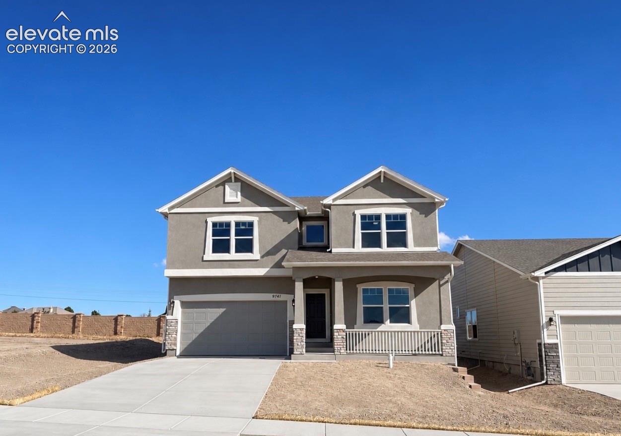 Two-story residence featuring a stucco facade, stone veneer accents, a covered front porch with a white railing, and an attached two-car garage