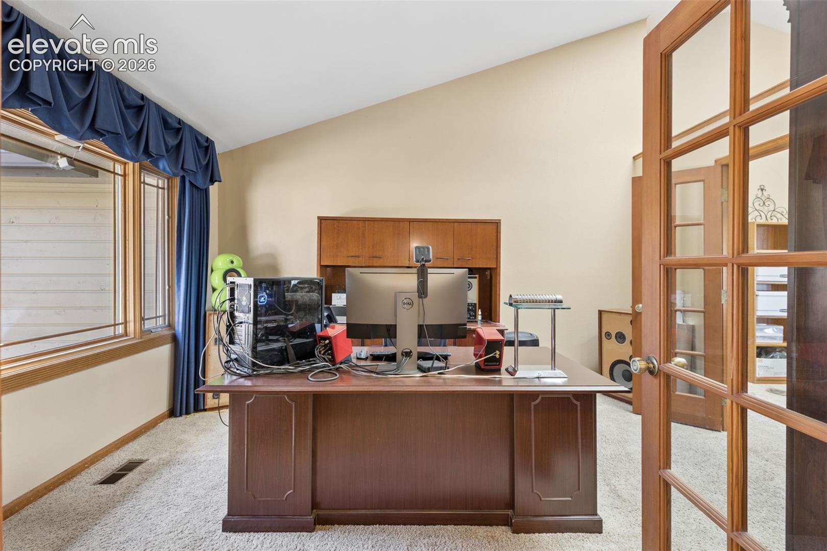Vaulted ceiling, wood-frame multi-pane French doors, and built-in wood cabinetry