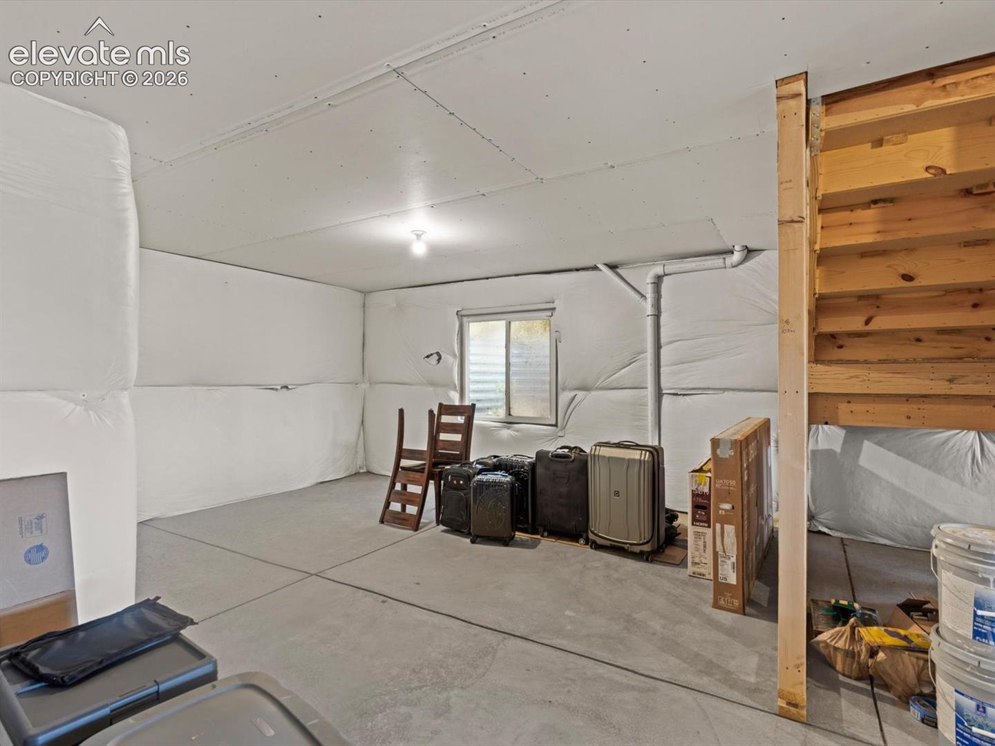 Unfinished basement with concrete flooring, exposed ceiling joists, and a perimeter drainage system