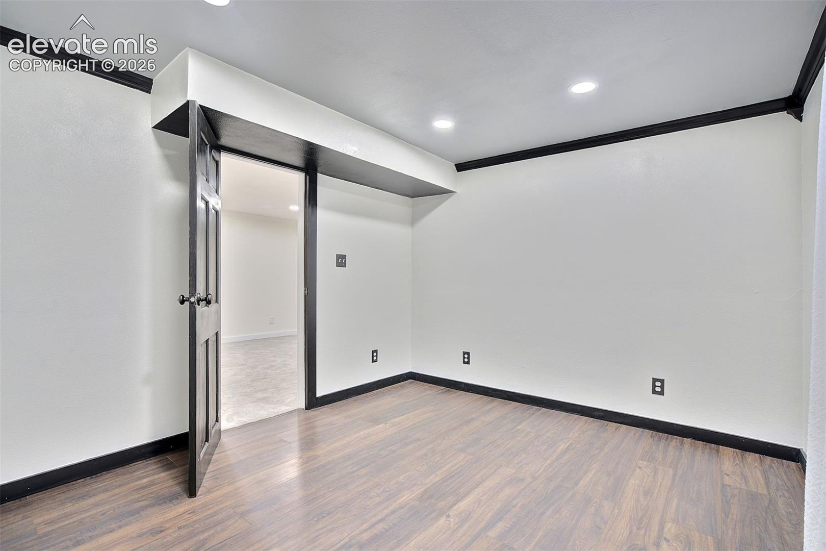 Interior space featuring wood-finish flooring, recessed lighting, and bold dark-toned crown molding and door trim