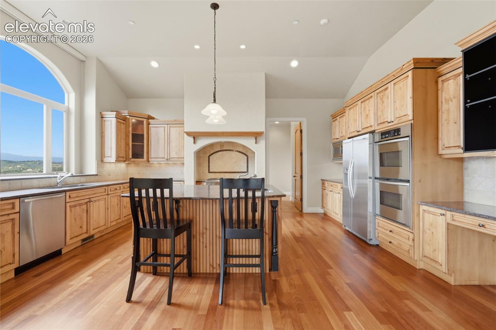 Hardwood flooring, arched window, stainless steel appliances, built-in double ovens, and recessed lighting