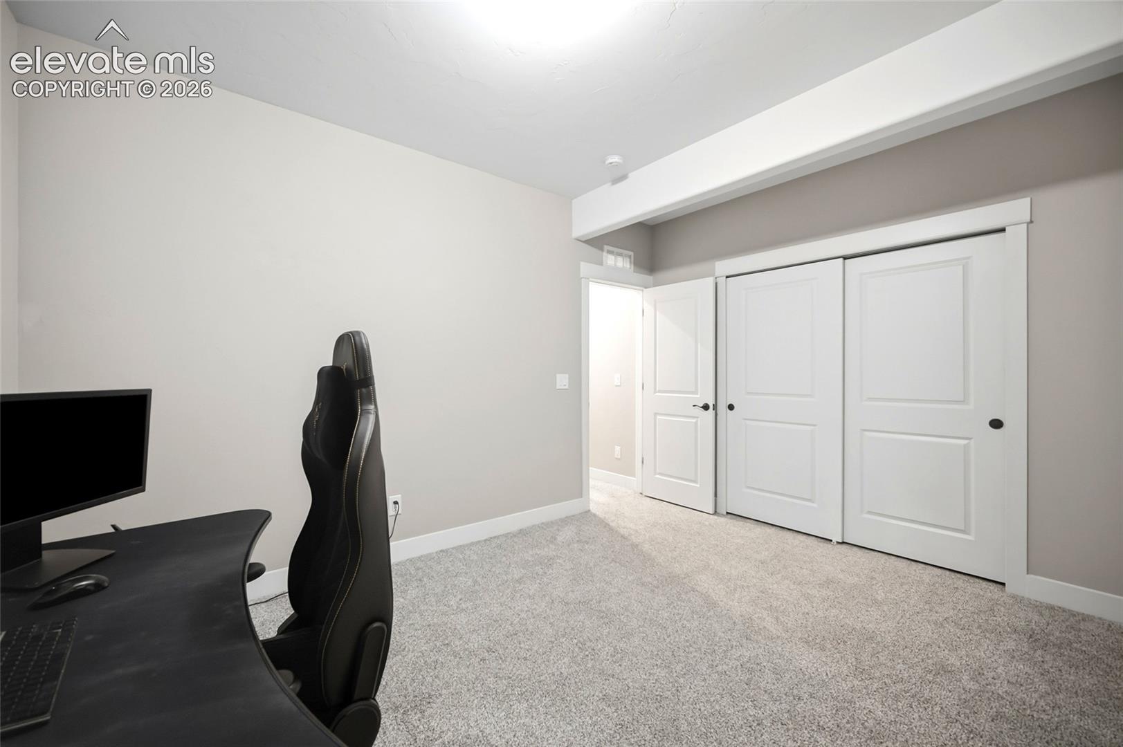 Neutral-toned interior featuring wall-to-wall carpeting, two-panel interior doors, a sliding-door closet system, and a prominent structural ceiling beam