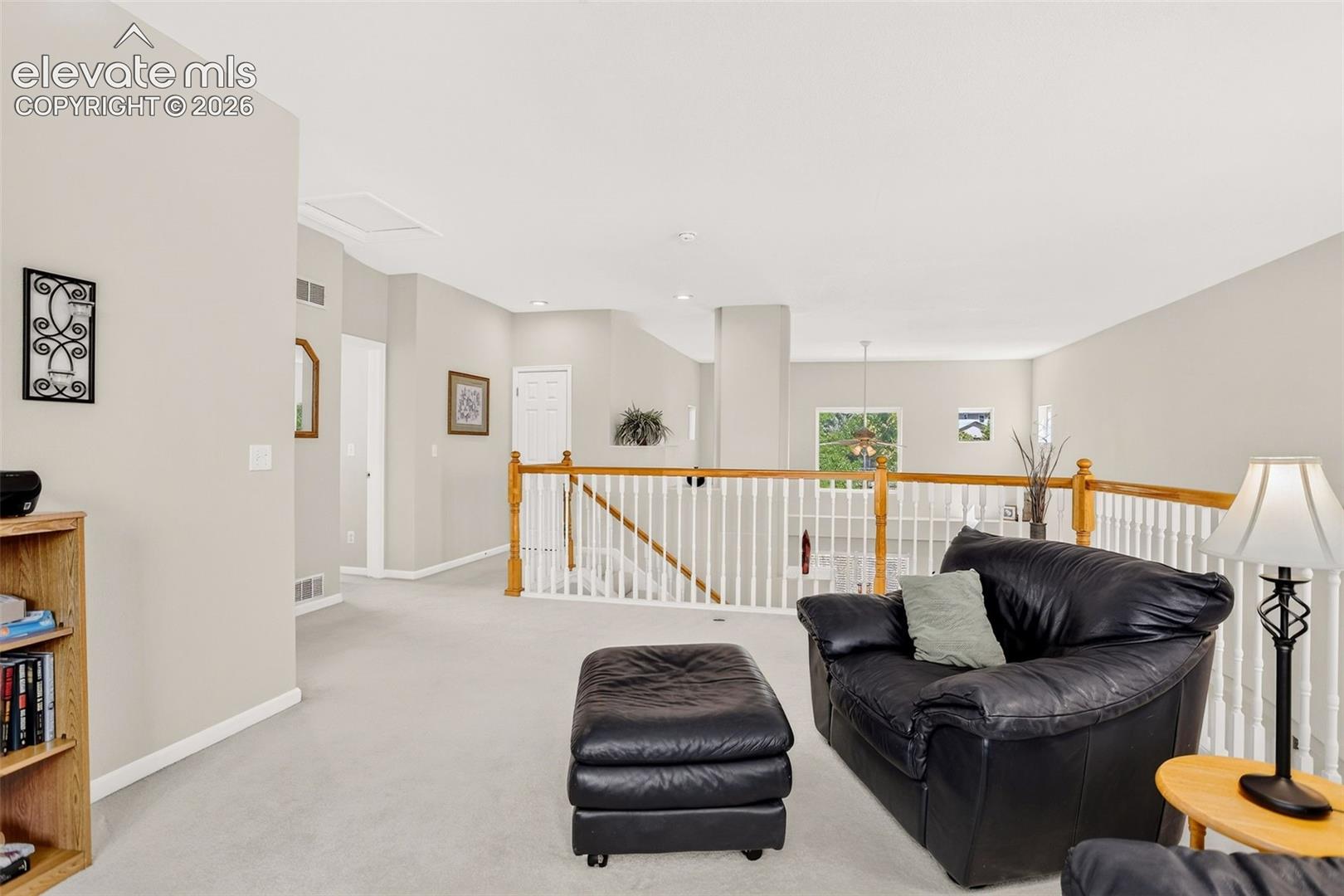 Carpeted upper level with painted walls, white railing with wood handrail, and an overhead light fixture