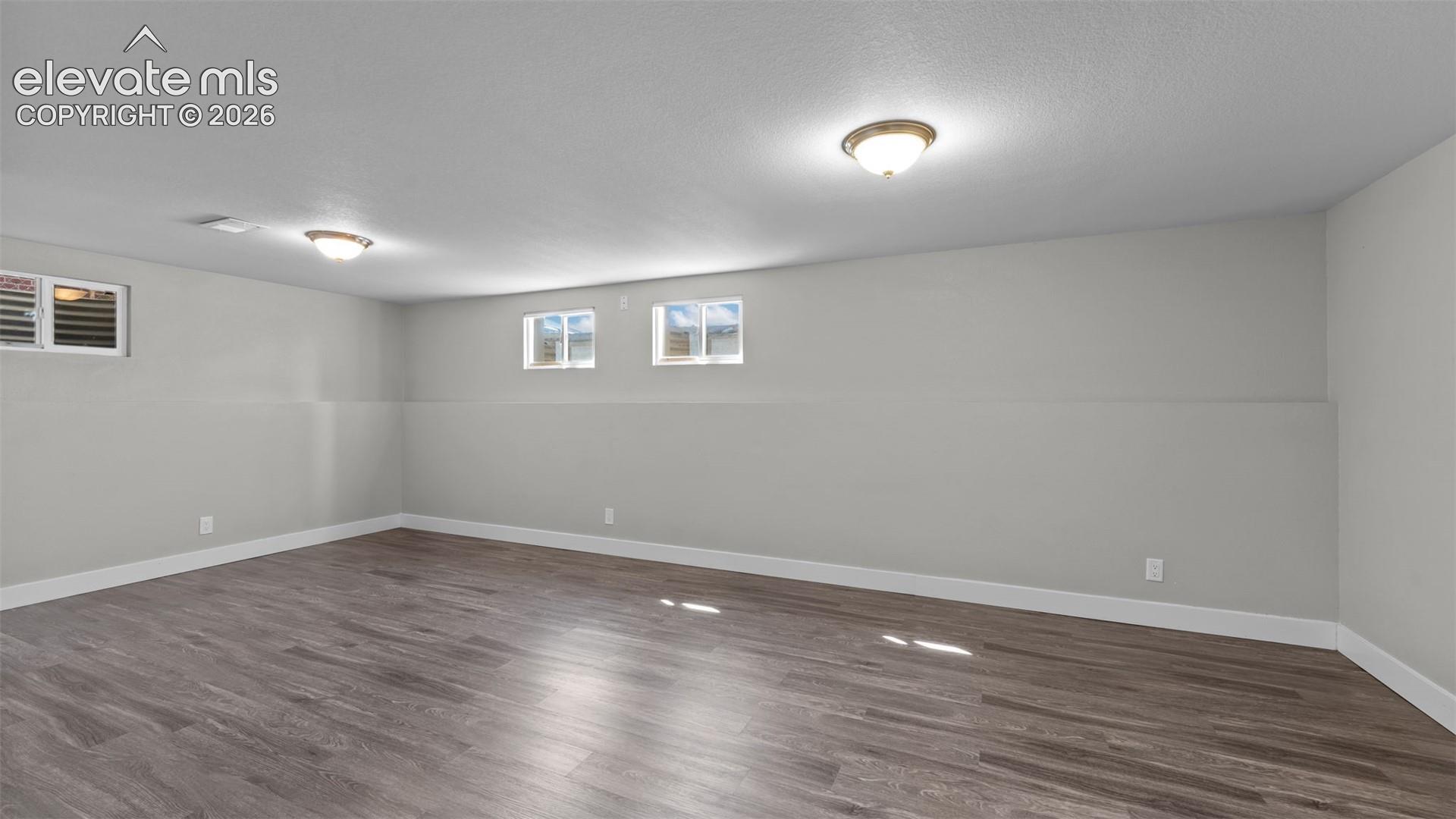 Spacious interior with wood-finish flooring, light grey wall paint, and recessed windows
