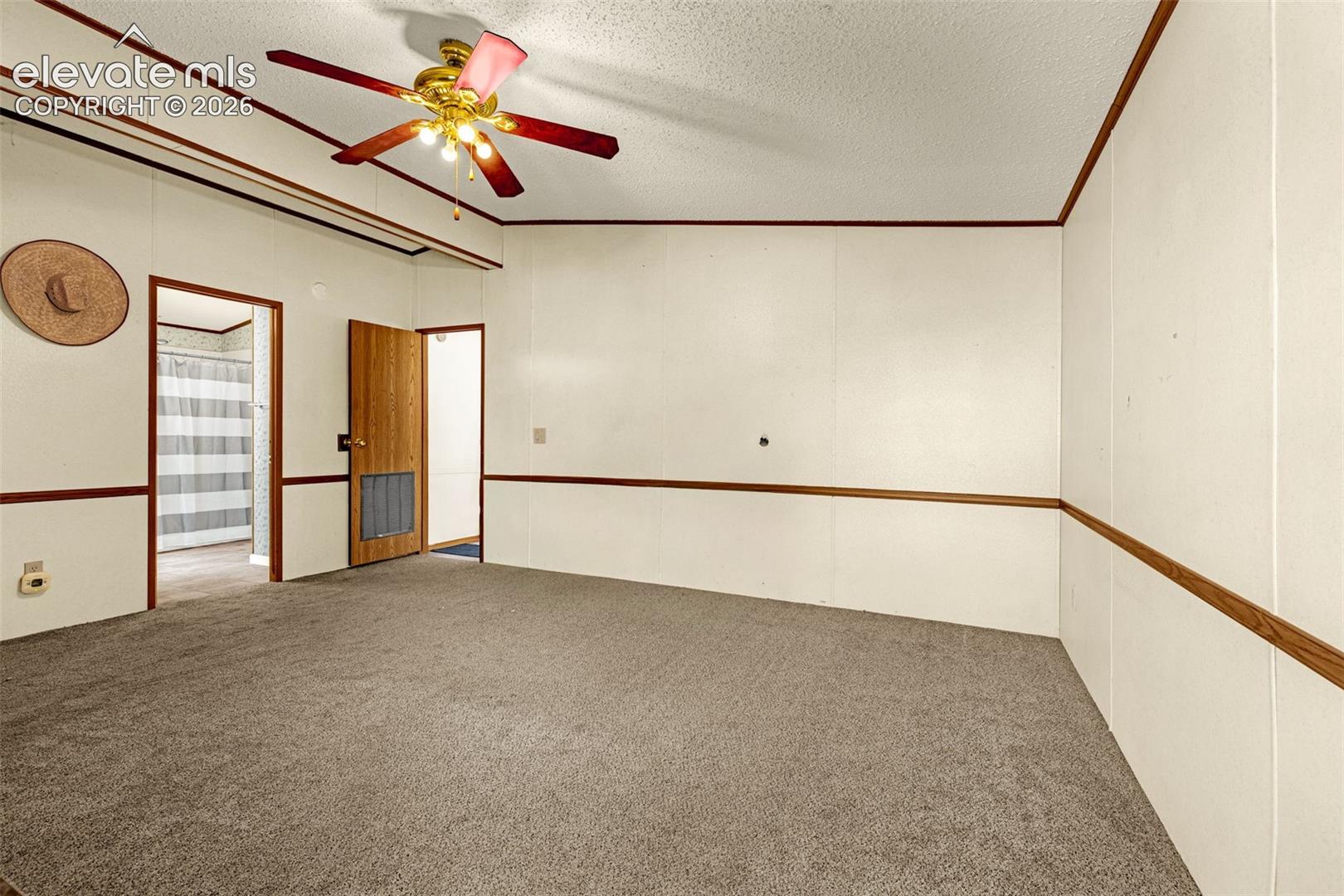 Interior space featuring wall-to-wall carpeting, ceiling fan with integrated lighting, and wood-trim chair rail molding