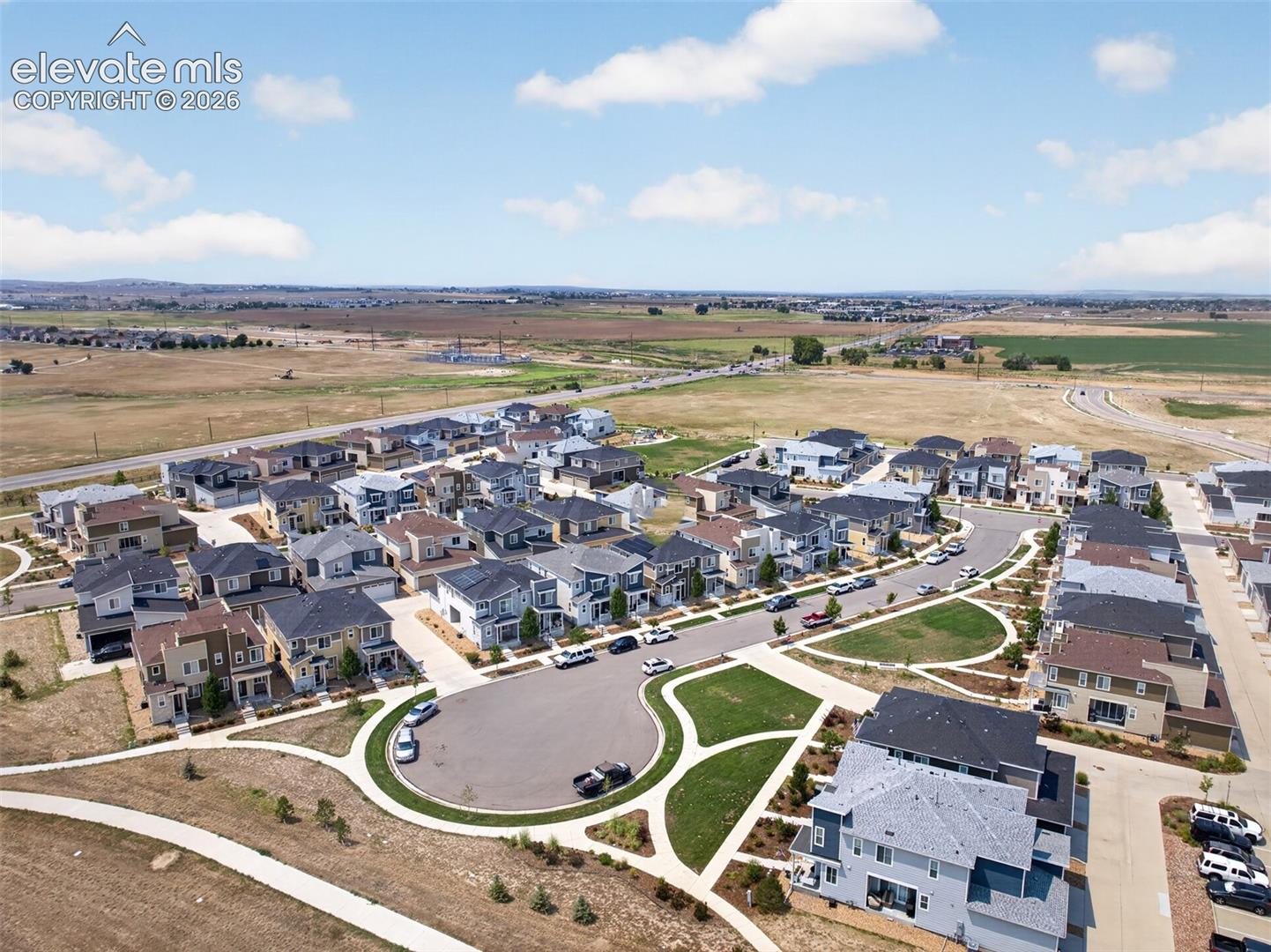 Aerial perspective of a planned community featuring multi-story residential structures, paved cul-de-sacs, integrated walking paths, and manicured green spaces