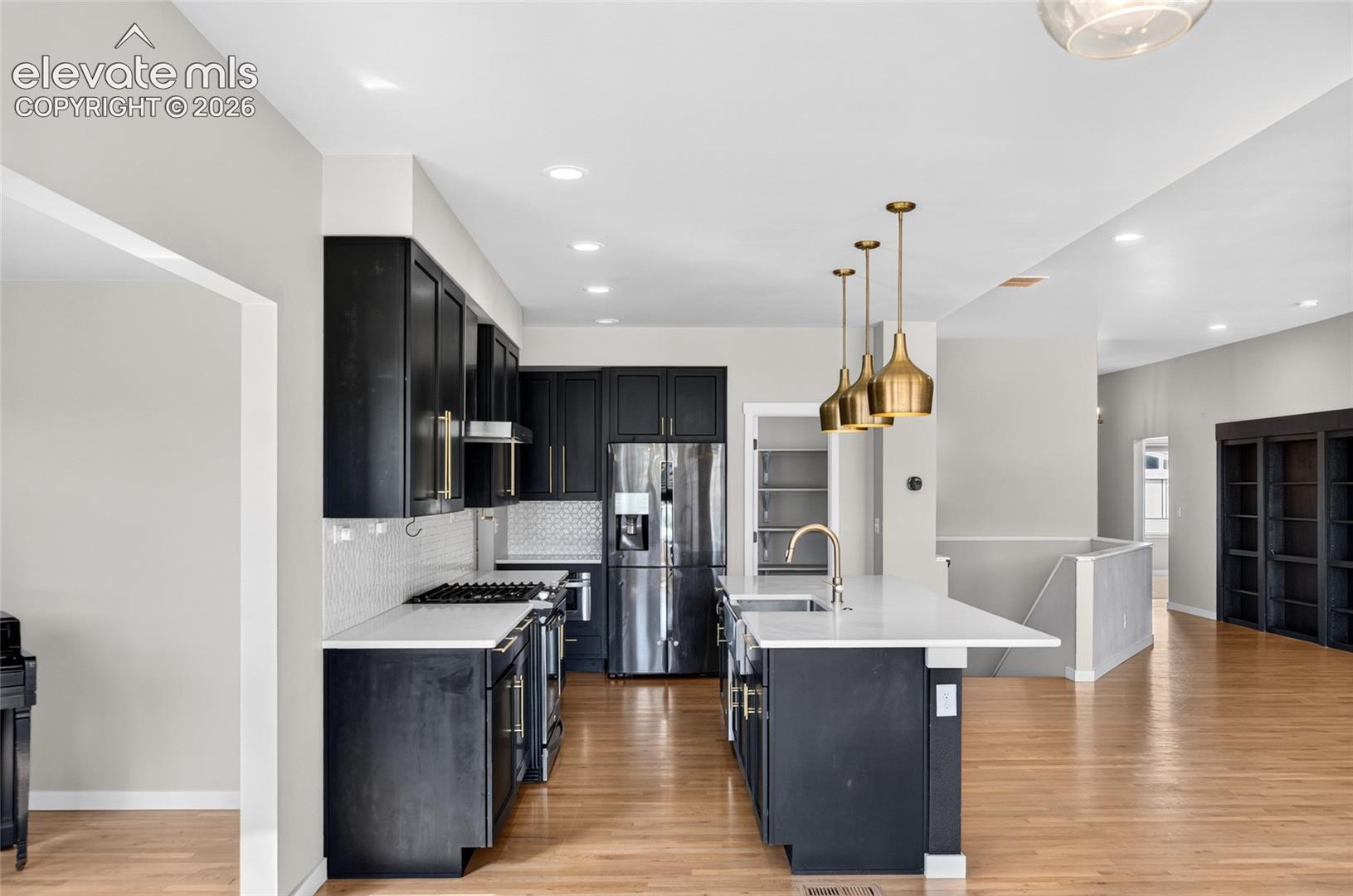 Modern kitchen featuring dark cabinetry, white countertops, a tiled backsplash, and stainless steel appliances