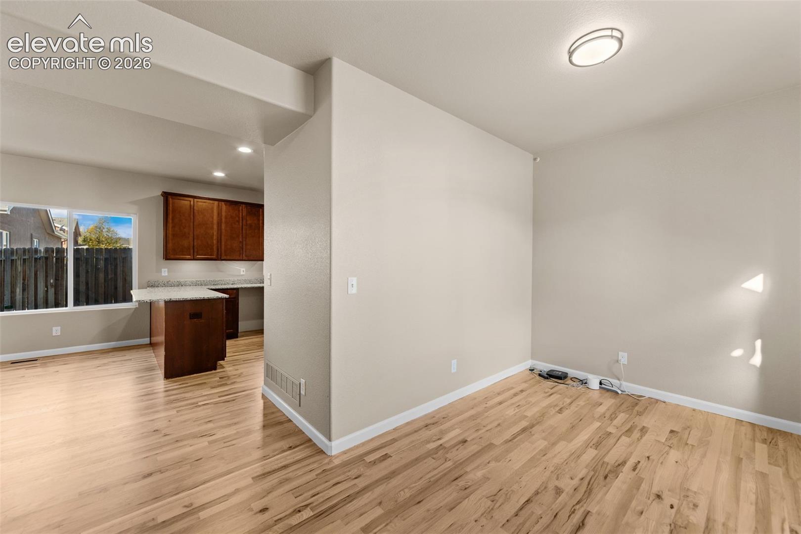 Open-concept interior featuring wood-finish flooring, recessed lighting, and a kitchen island with stone-finish countertops and dark wood cabinetry