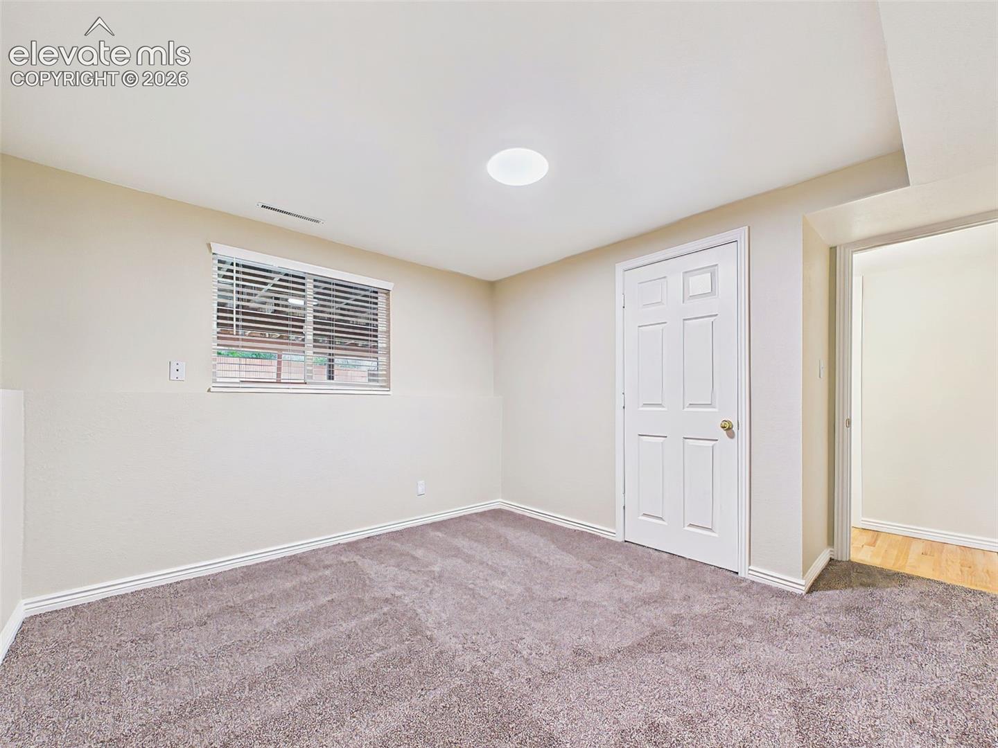 Versatile lower-level bonus room with brand-new carpet and natural light, perfect for a home office, fitness room, hobby space, or additional guest accommodations.