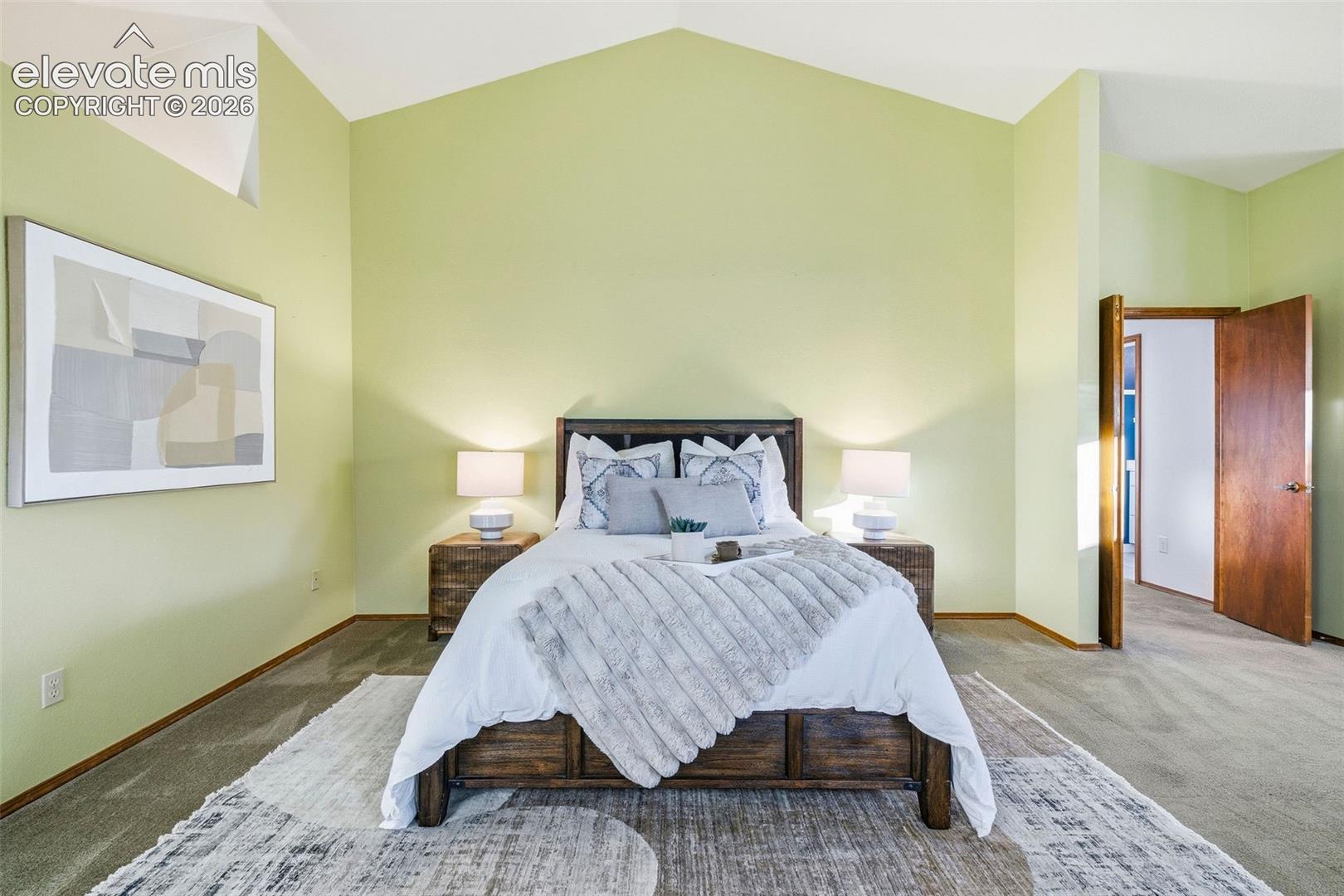 Vaulted ceiling, interior wooden door, and neutral carpeting