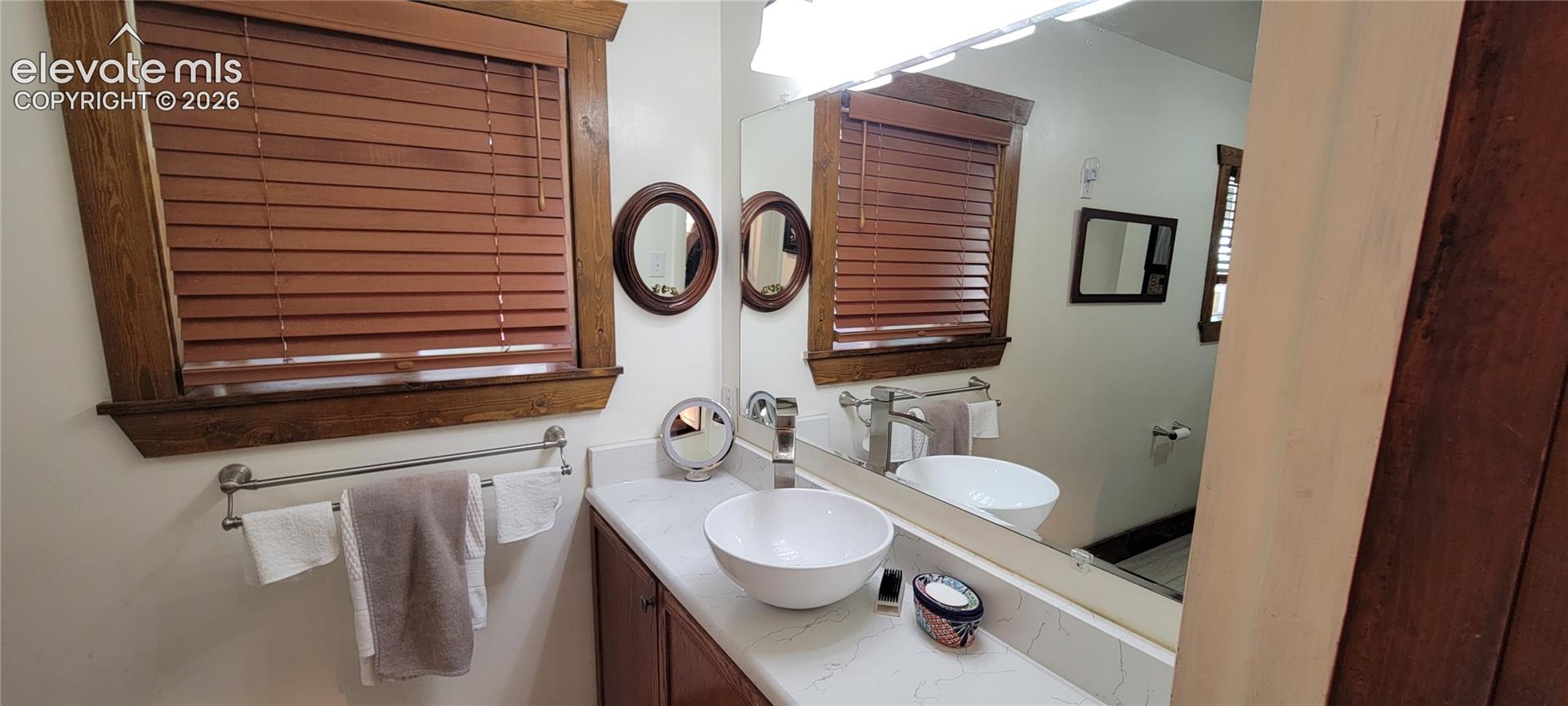 Bathroom vanity featuring a vessel sink, single-handle faucet, and white countertop