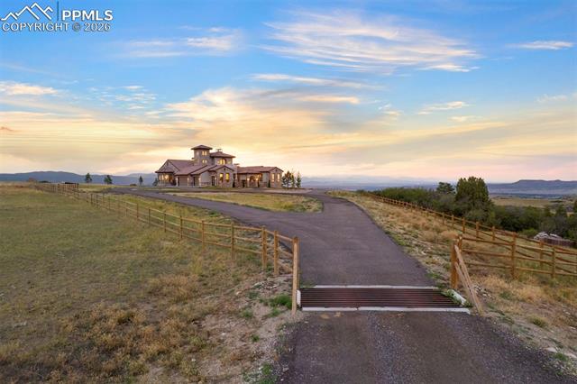 Golden hour light pours over the hilltop setting,accentuating the circular drive that leads to thee state.