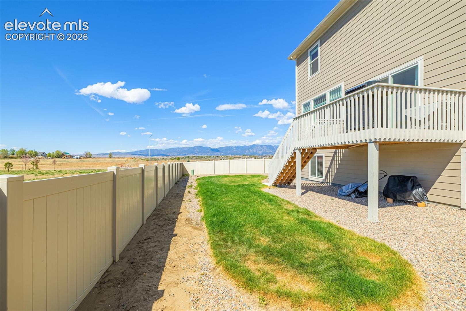 Expansive backyard with a manicured lawn, gravel landscaping, and a tan privacy fence