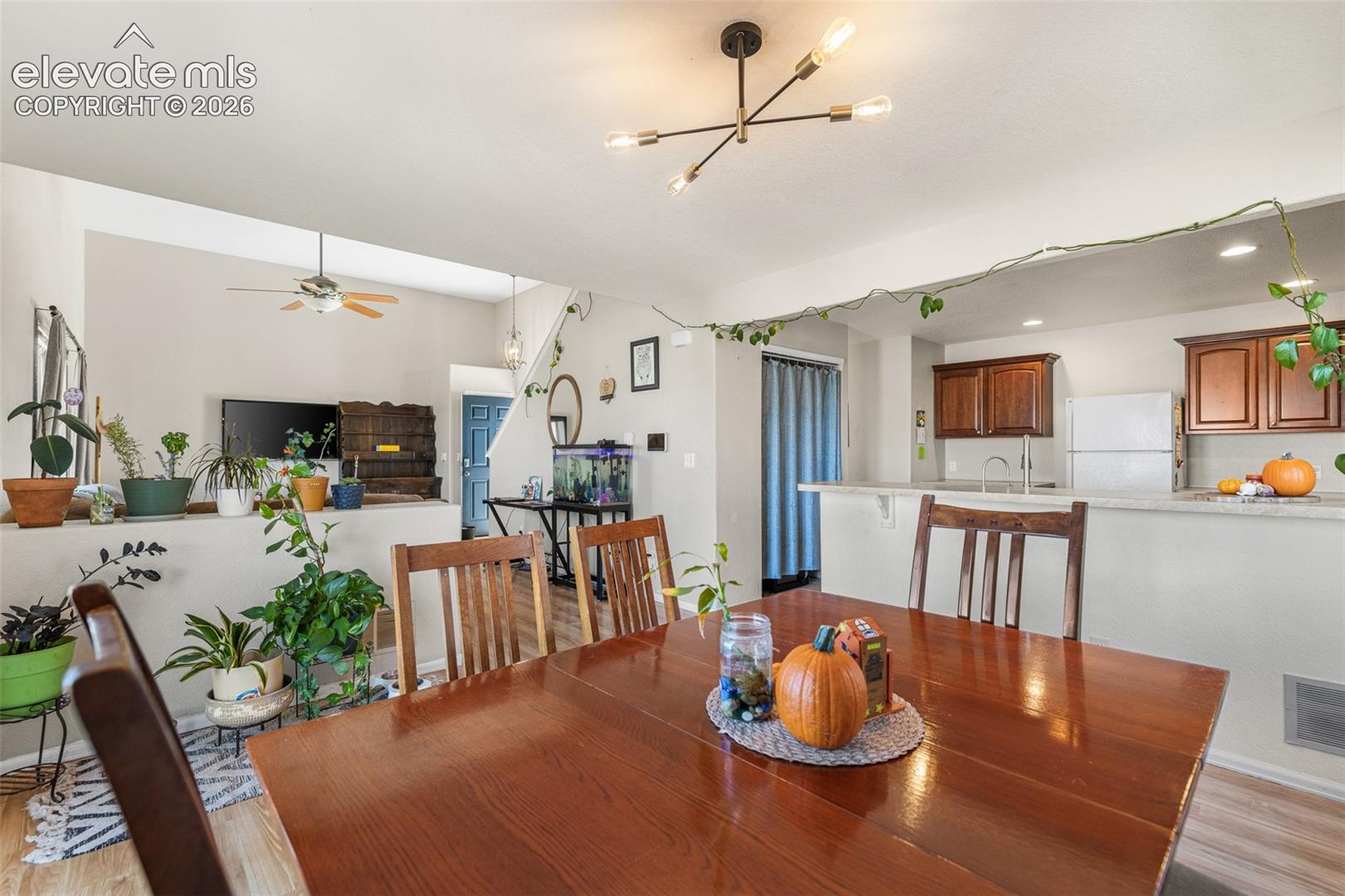 Open-concept interior featuring wood-finish flooring, dark wood cabinetry, a breakfast bar, and a multi-arm geometric ceiling fixture