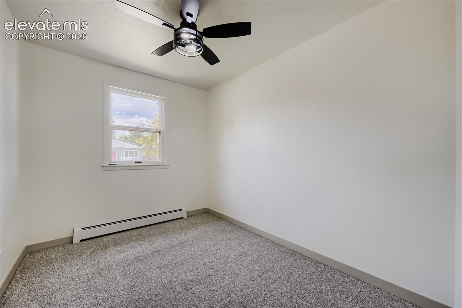 Neutral wall paint with gray carpeting, featuring a ceiling fan with black blades and a double-hung window