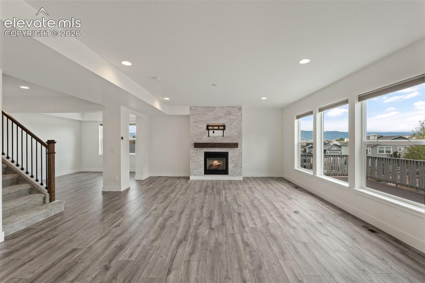 Spacious living area featuring wood-finish flooring, a stone-clad fireplace with a wood mantel, and mountain views 