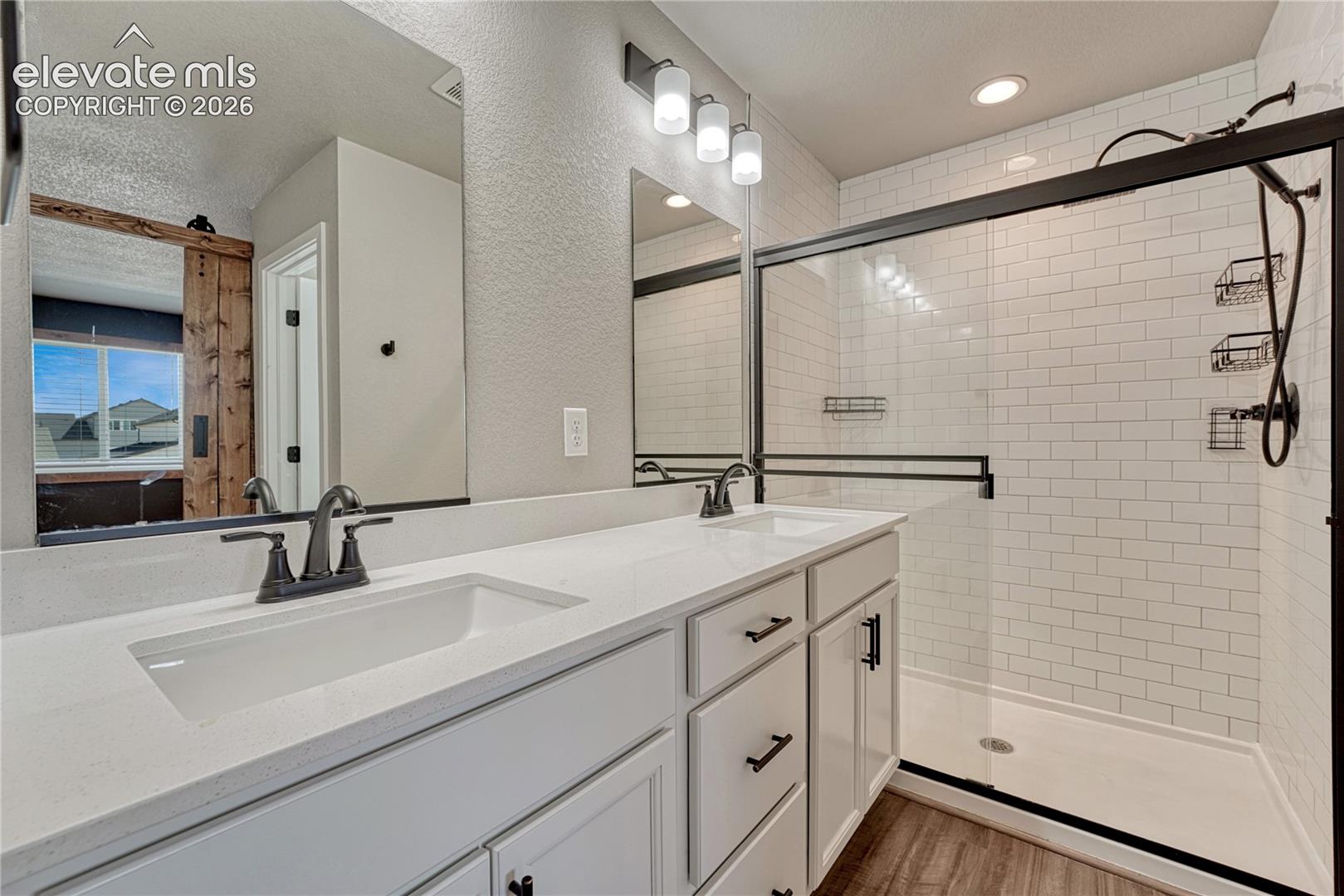 Primary bathroom has quartz countertops, luxury vinyl flooring and subway tile. 