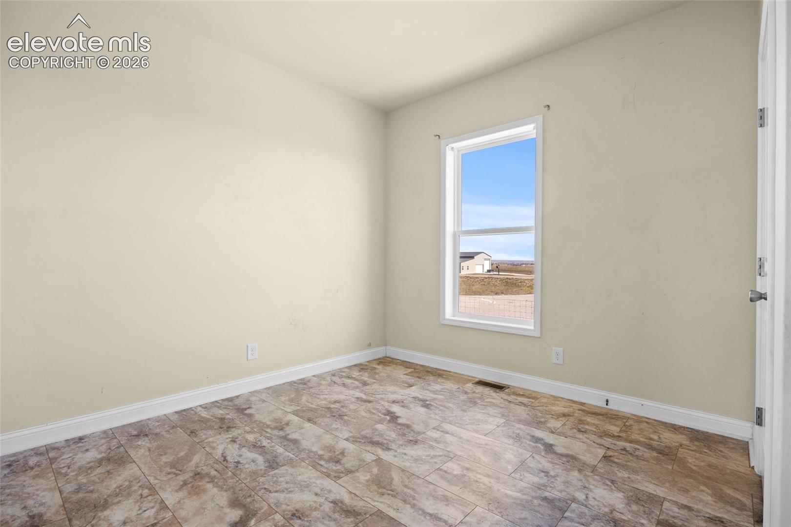Room featuring neutral-toned walls, rectangular tile flooring, and a single-hung window with exterior landscape exposure