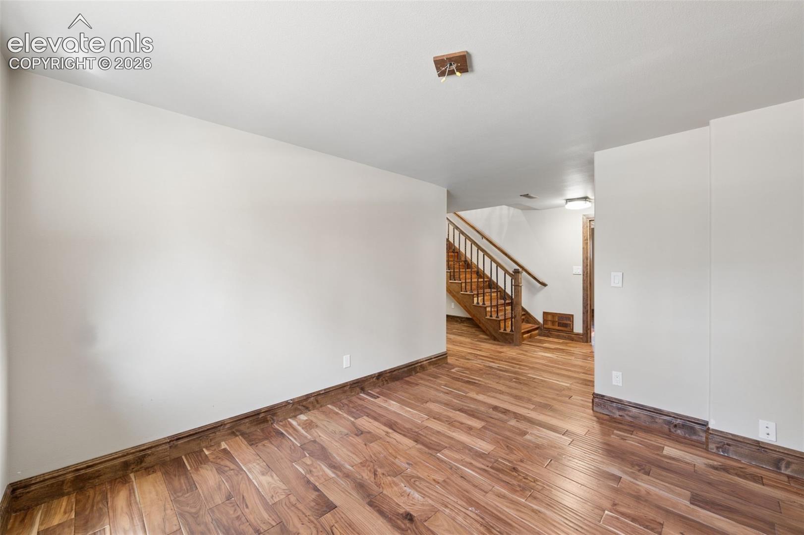 Wood-finish flooring, wood staircase with matching handrail, and neutral wall tones