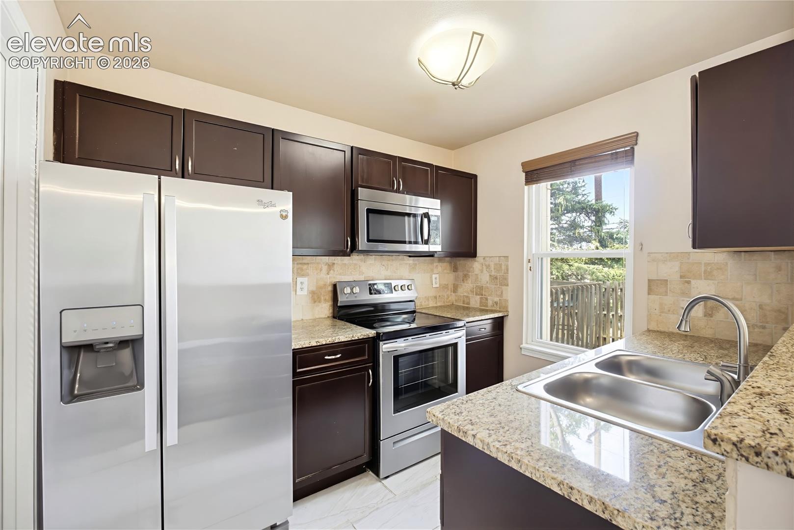 The Kitchen features wood cabinets with countertops and stainless steel appliances including a smooth top range oven, microwave, dishwasher, and side by side refrigerator.