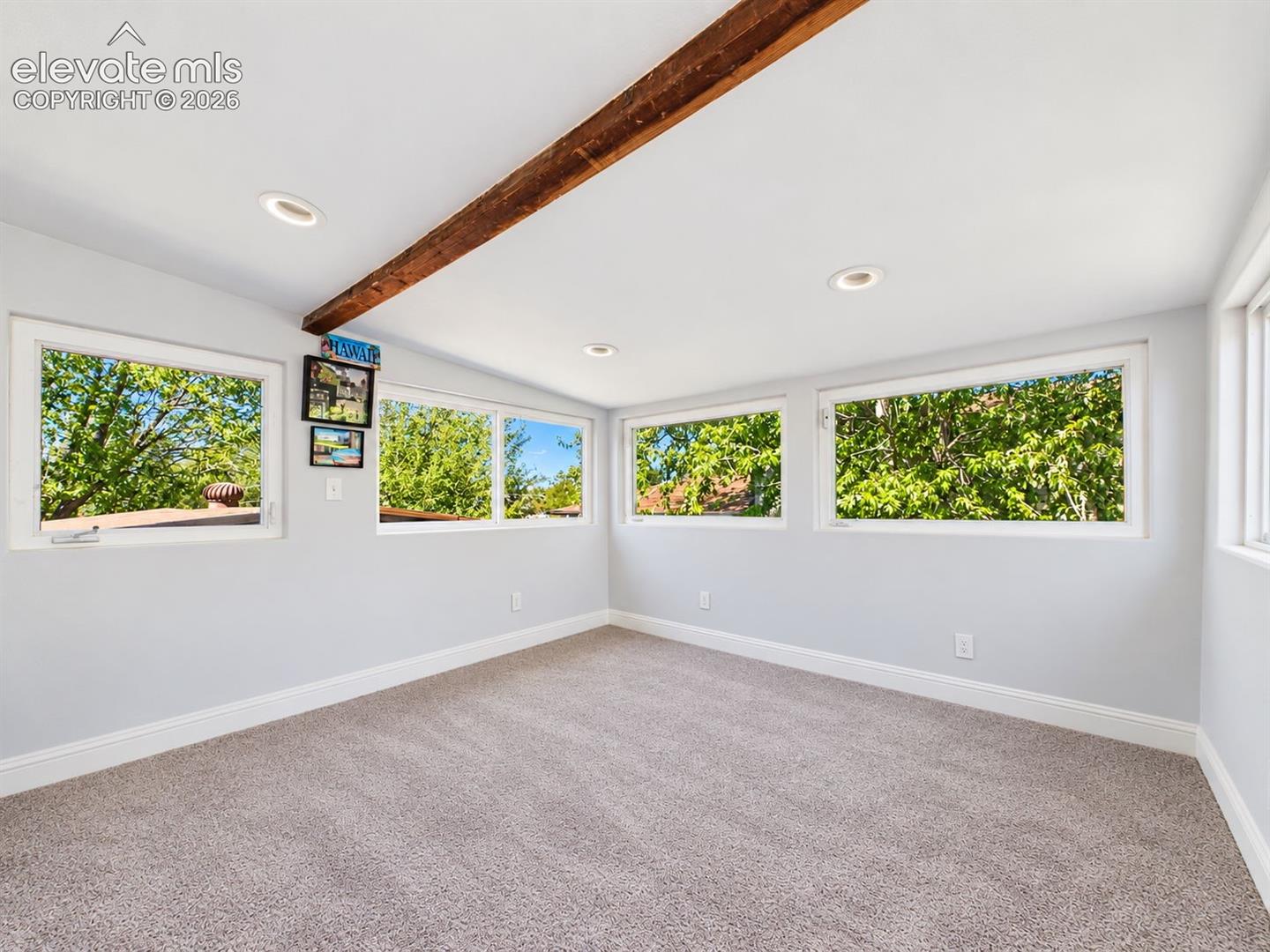 Walls of windows fill this flexible bonus space with natural light and leafy views, while the exposed wood beam adds warmth and character.