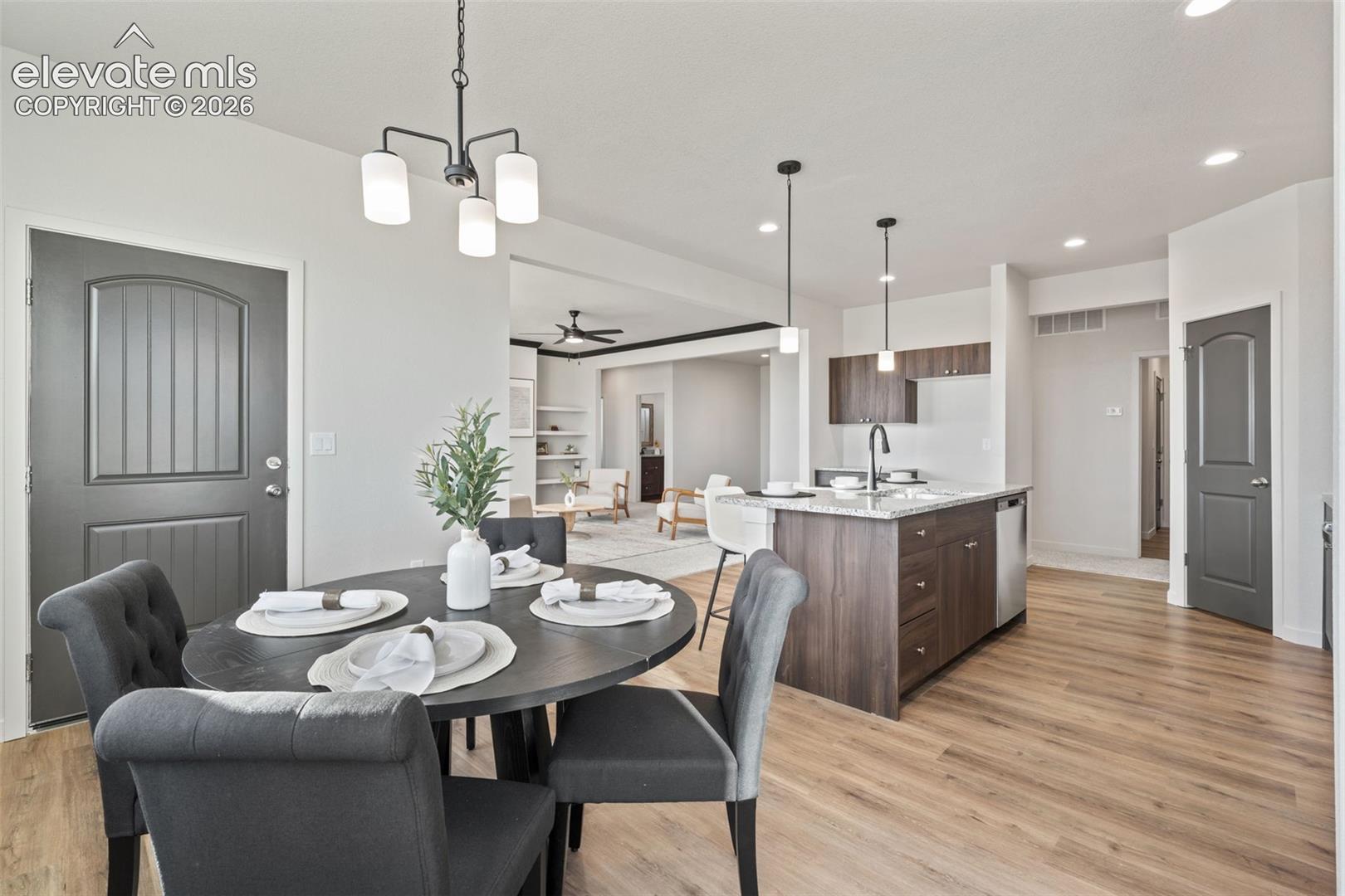 Open-concept dining area with wood-finish flooring, modern chandelier, and recessed lighting