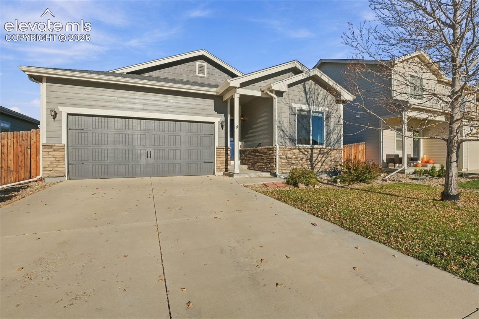 Exterior featuring horizontal siding, stone veneer accents, an attached two-car garage, and a concrete driveway