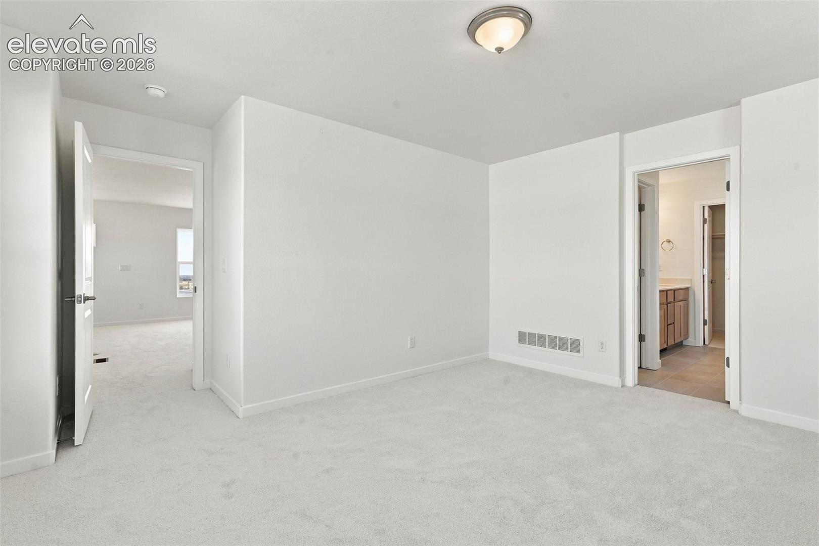 Light-toned wall-to-wall carpeting, white painted walls, and ceiling-mounted light fixture