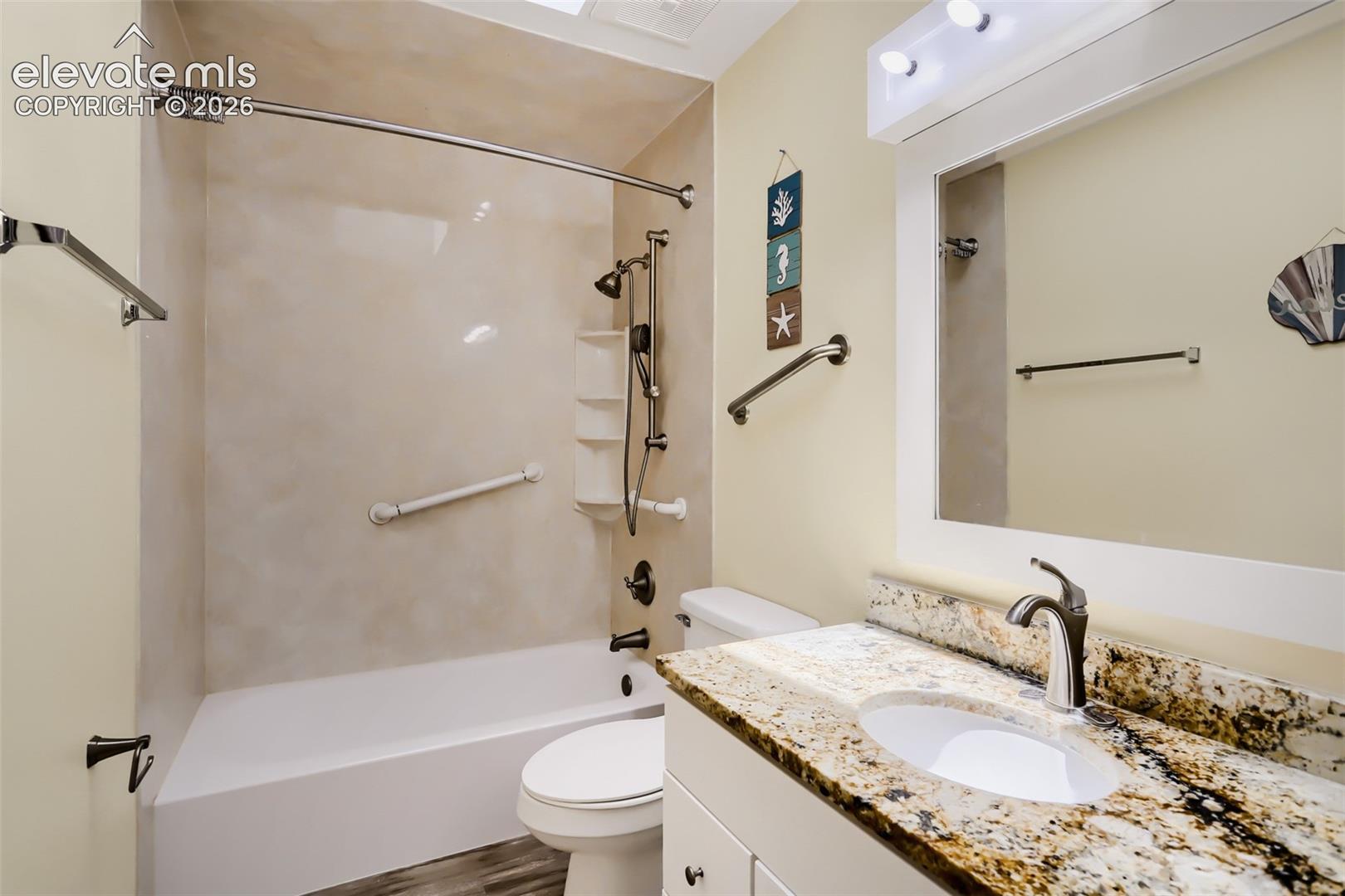 Bathroom featuring a vanity with a stone-finish countertop, undermount sink, and a framed mirror