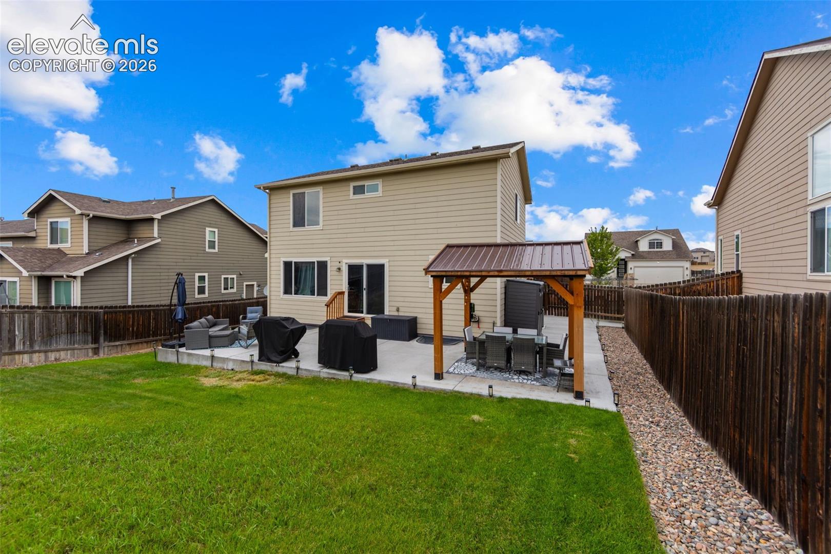 Expansive backyard featuring a lush lawn, concrete patio, and a covered pergola