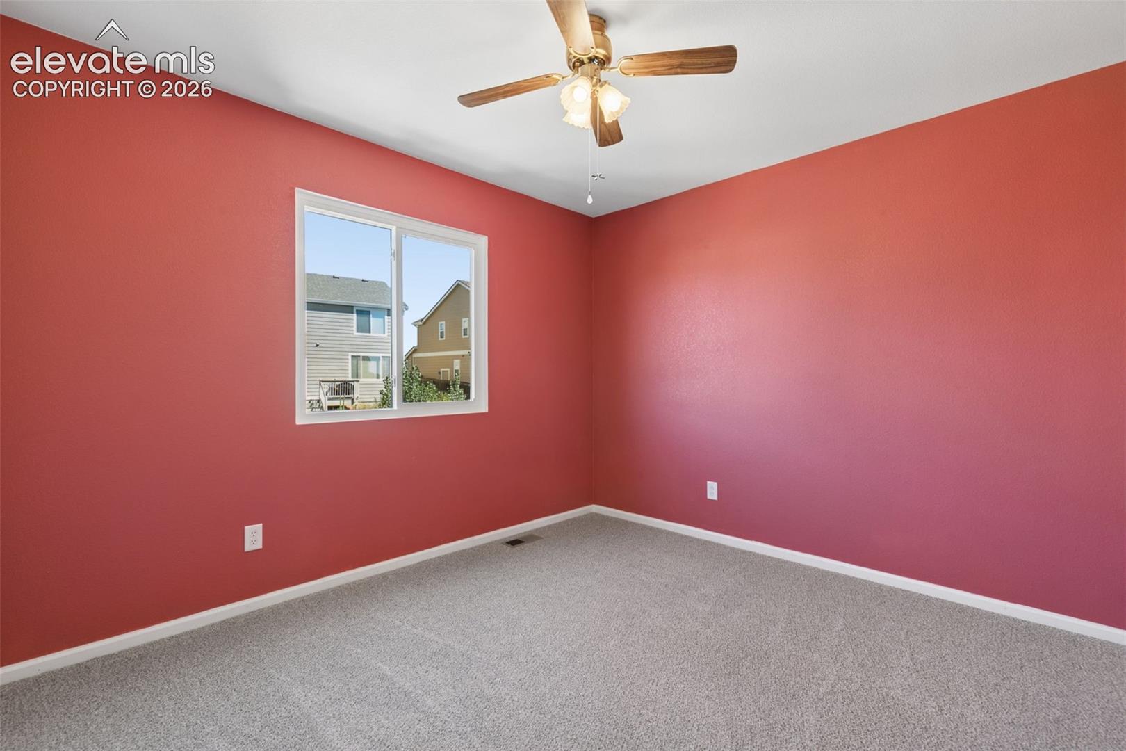 Window-equipped room featuring a ceiling fan with integrated lighting, neutral-toned carpeting, and light-colored trim